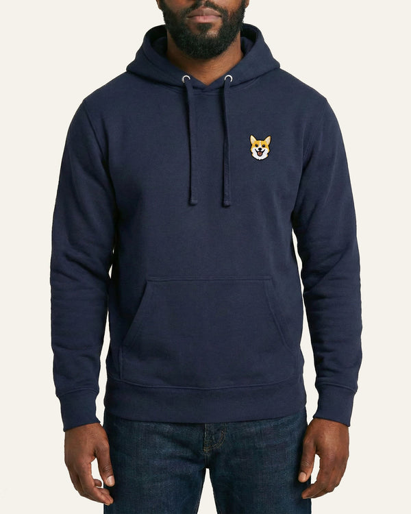 Man wearing Navy Hoodie with minimalist embroidered Corgi icon on left chest.