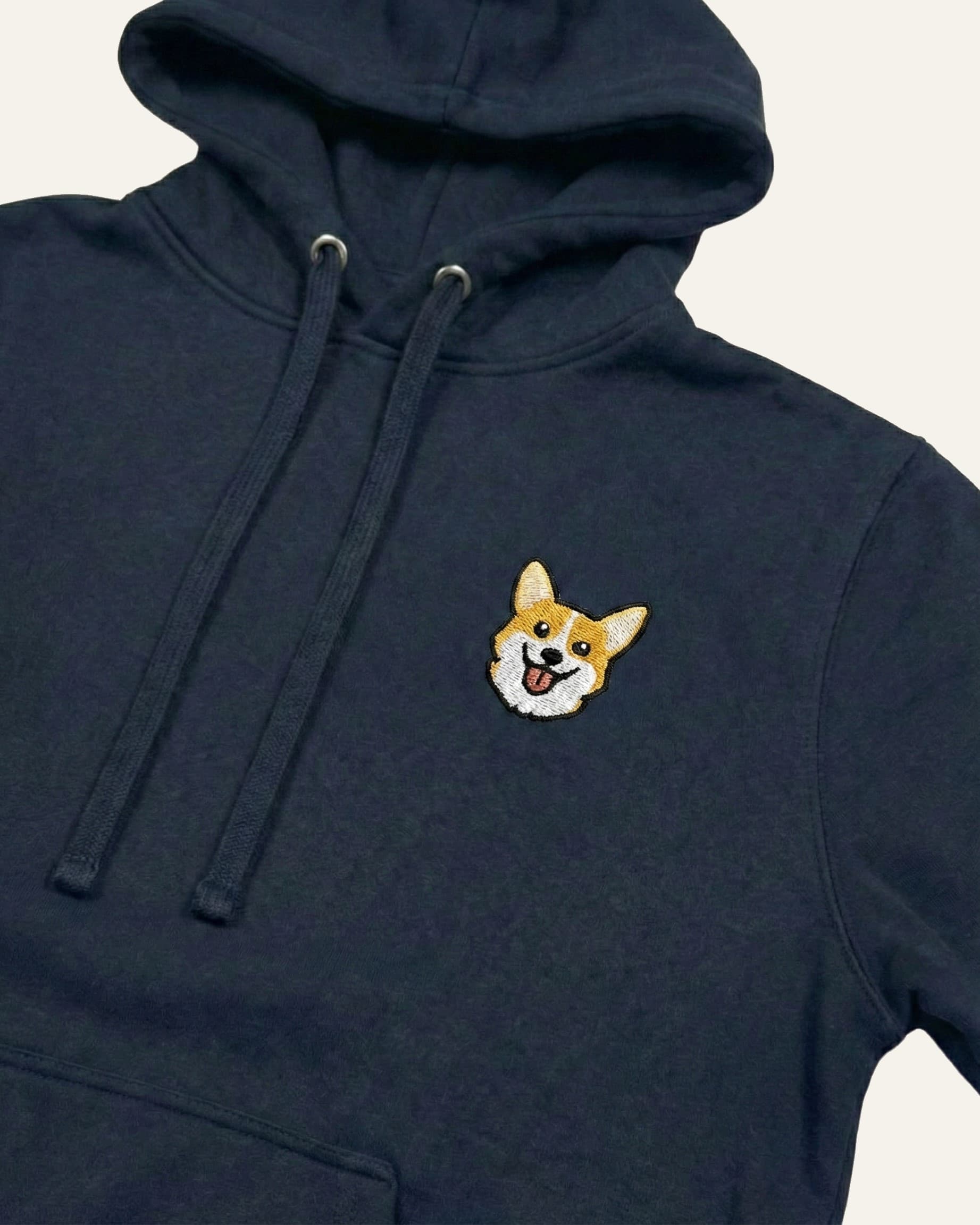 Close up of Navy Hoodie with minimalist embroidered Corgi icon on left chest.