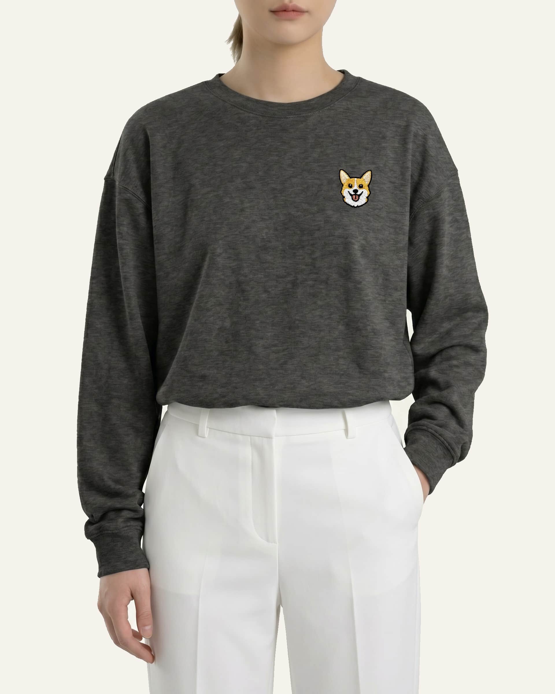 Woman wearing Dark Grey Heather Sweatshirt with minimalist embroidered Corgi icon on left chest.