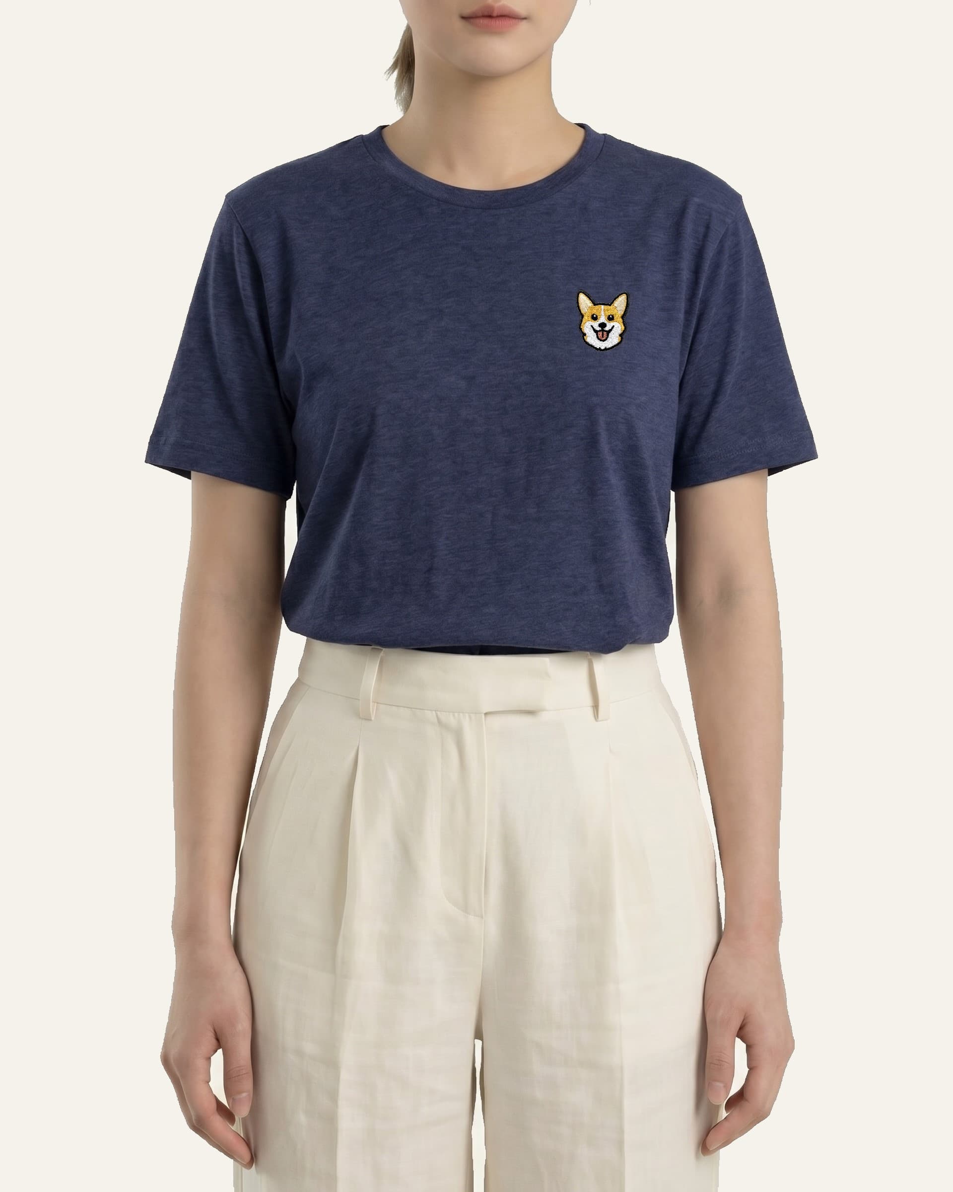 Woman wearing Navy Heather T-shirt with minimalist embroidered Corgi icon on left chest.