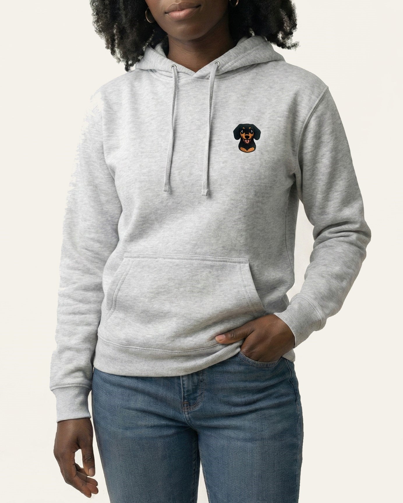 Woman wearing Light Grey Heather Hoodie with minimalist embroidered Dachshund icon on left chest.