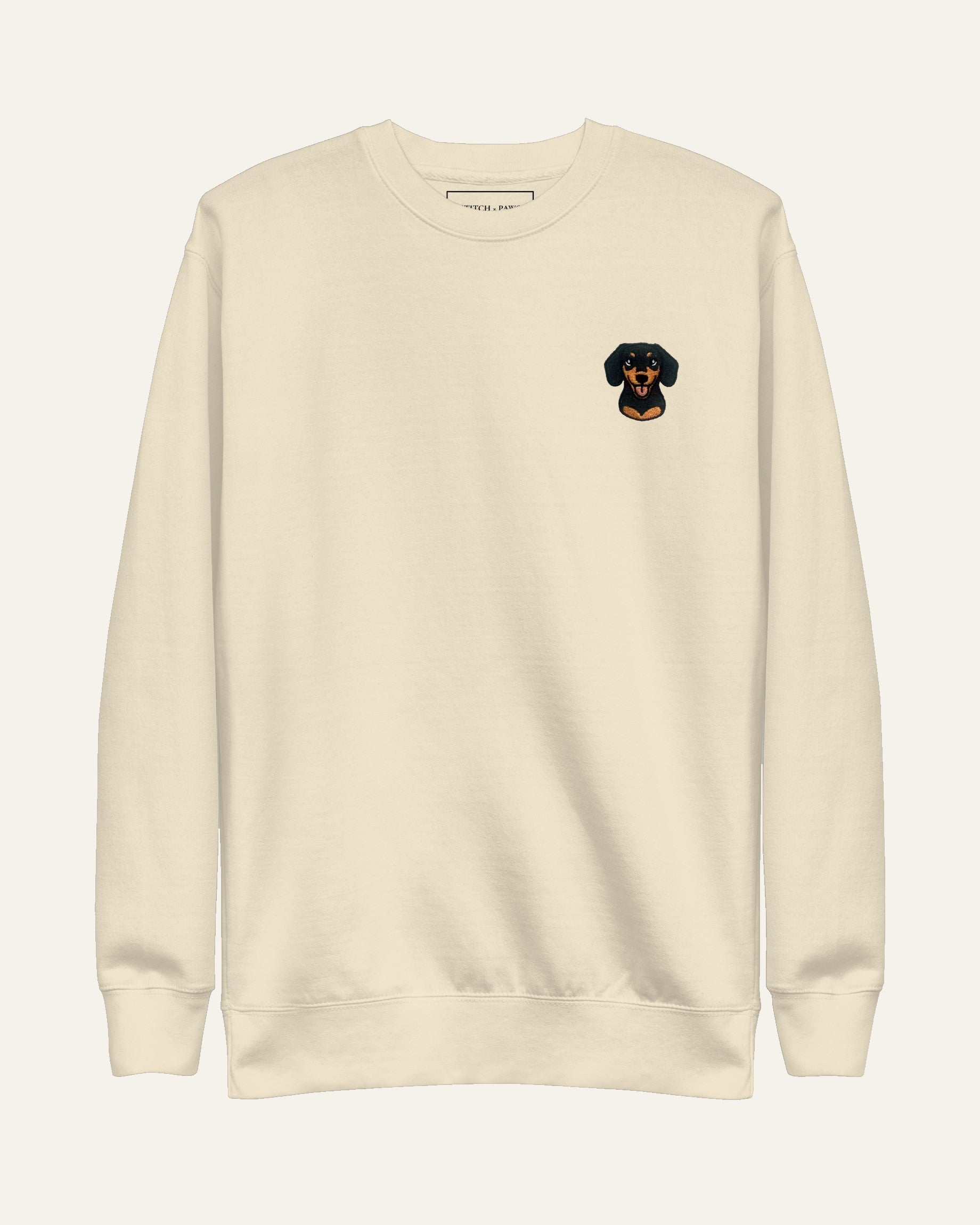 Light Beige Sweatshirt with minimalist embroidered Dachshund icon on left chest.