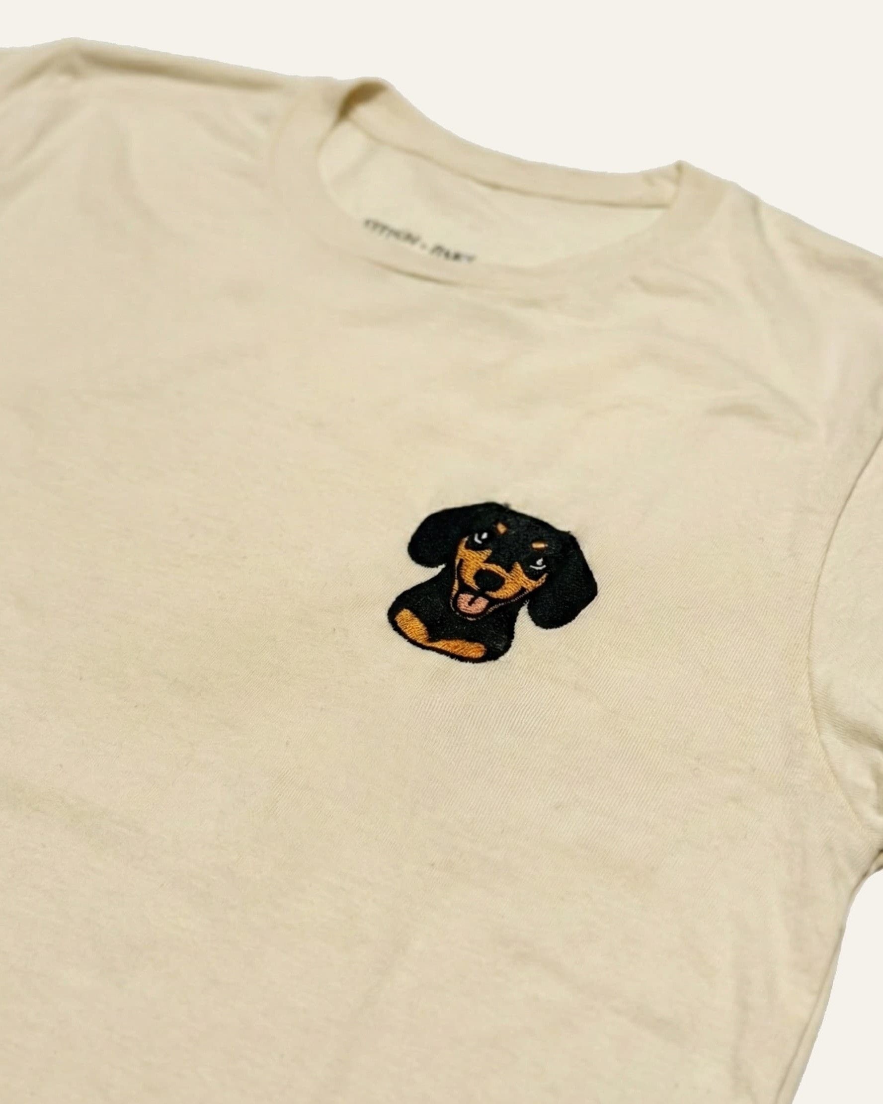 Light Beige T-shirt with minimalist embroidered Dachshund icon on left chest.