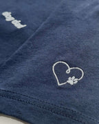 Close up of Navy t-shirt with minimalist embroidered phrase "dog dad" on left chest. Embroidered Heart and Paw icon on the left sleeve above cuff.