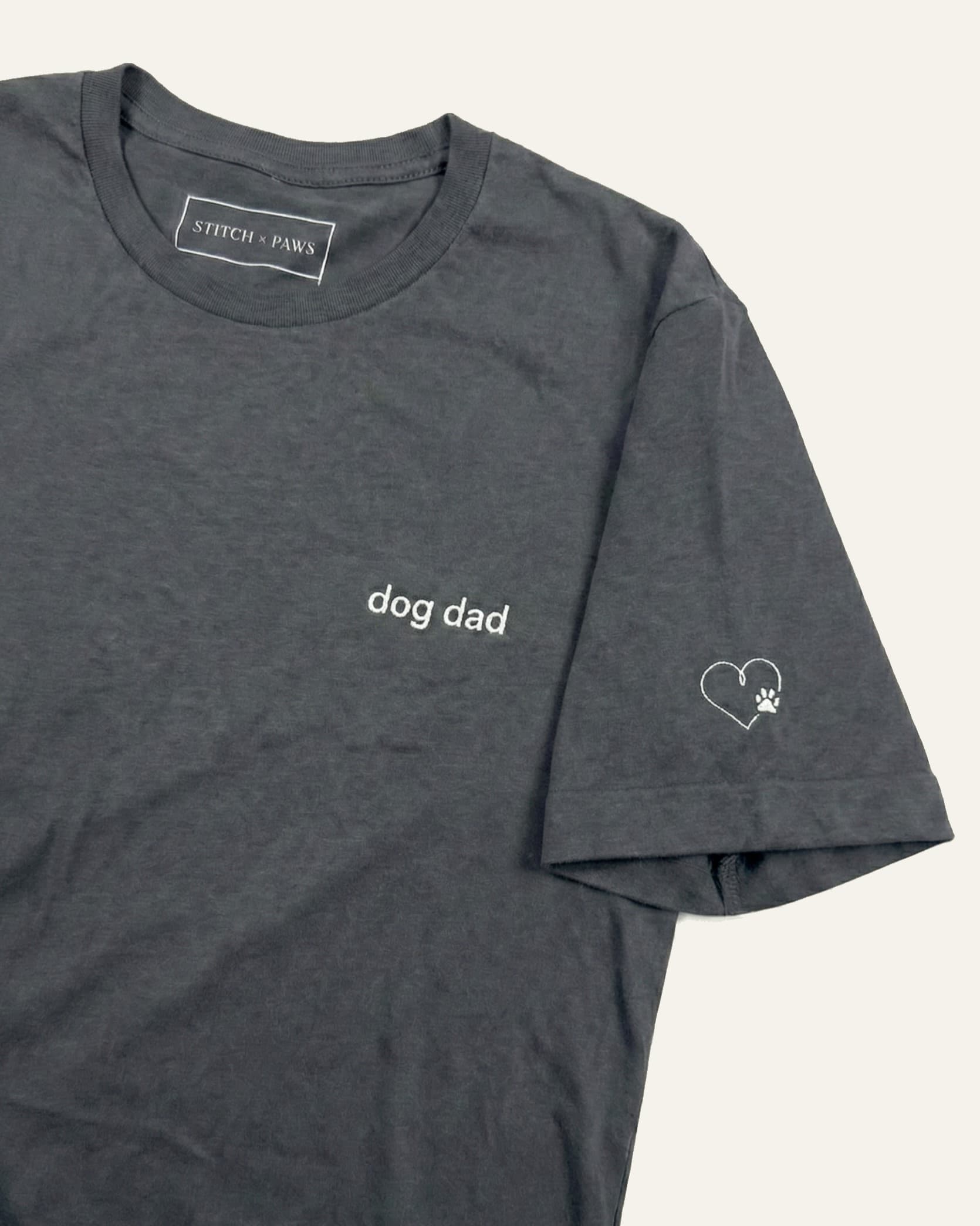 Asphalt t-shirt with minimalist embroidered phrase "dog dad" on left chest. Embroidered Heart and Paw icon on the left sleeve above cuff.