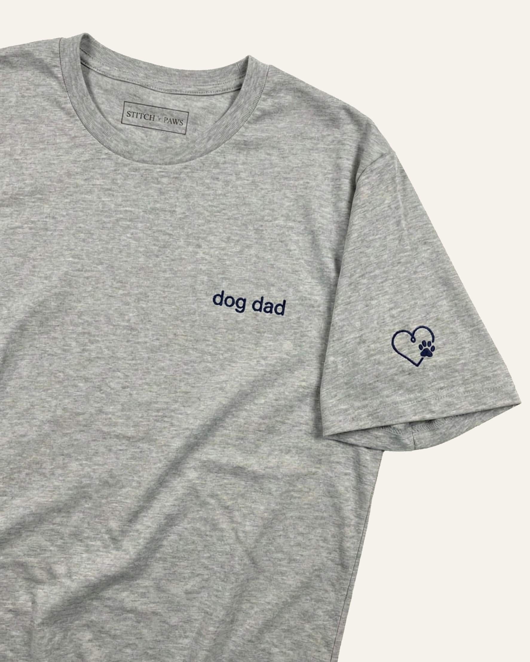 Light Grey Heather t-shirt with minimalist embroidered phrase "dog dad" on left chest. Embroidered Heart and Paw icon on the left sleeve above cuff.