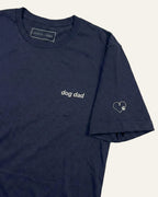 Navy t-shirt with minimalist embroidered phrase "dog dad" on left chest. Embroidered Heart and Paw icon on the left sleeve above cuff.
