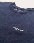 Close up of Navy t-shirt with minimalist embroidered phrase "dog dad" on left chest.