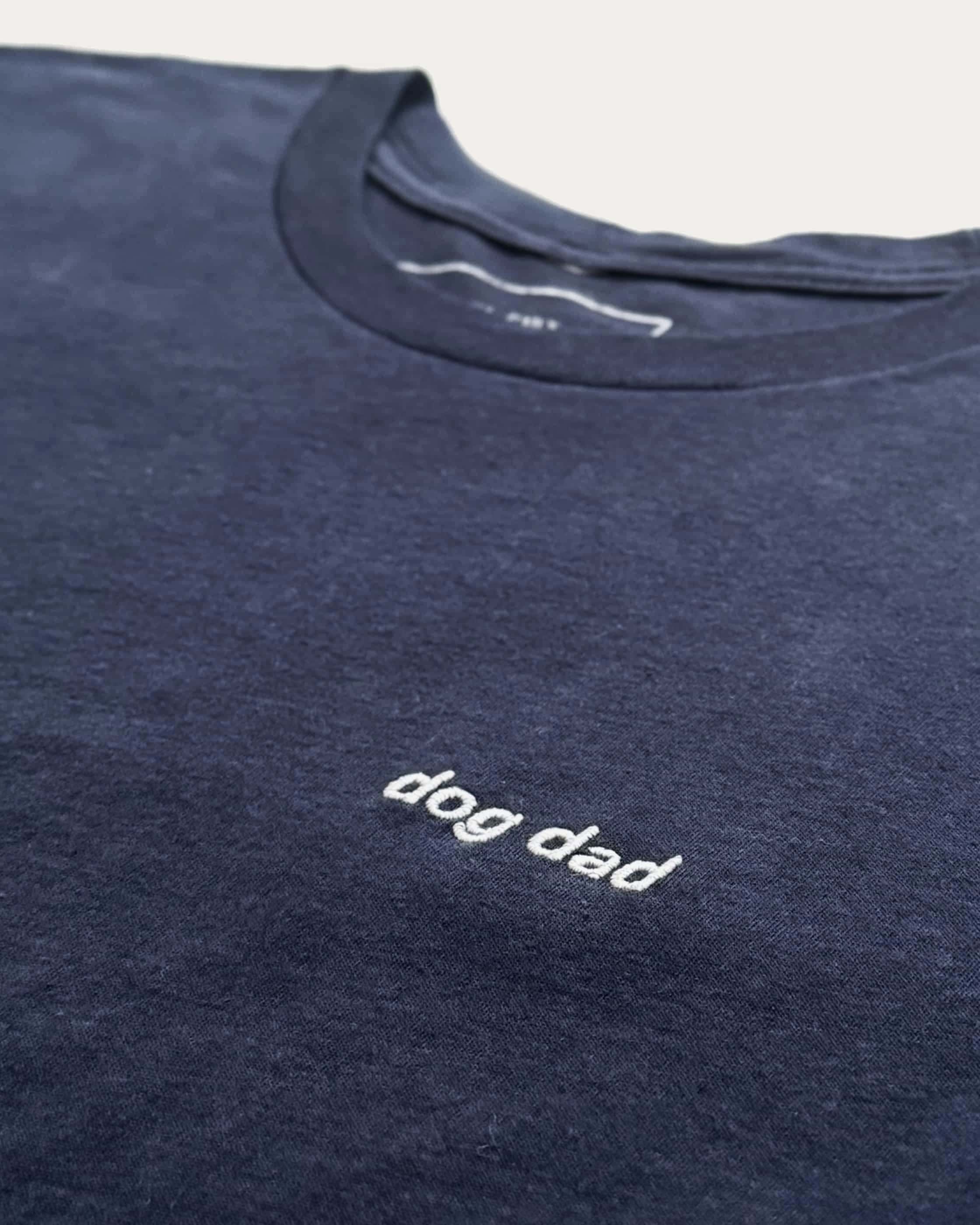 Close up of Navy t-shirt with minimalist embroidered phrase "dog dad" on left chest.