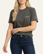 Woman wearing Asphalt t-shirt with minimalist embroidered phrase "dog mom" on left chest. Embroidered Heart and Paw icon on the left sleeve above cuff.