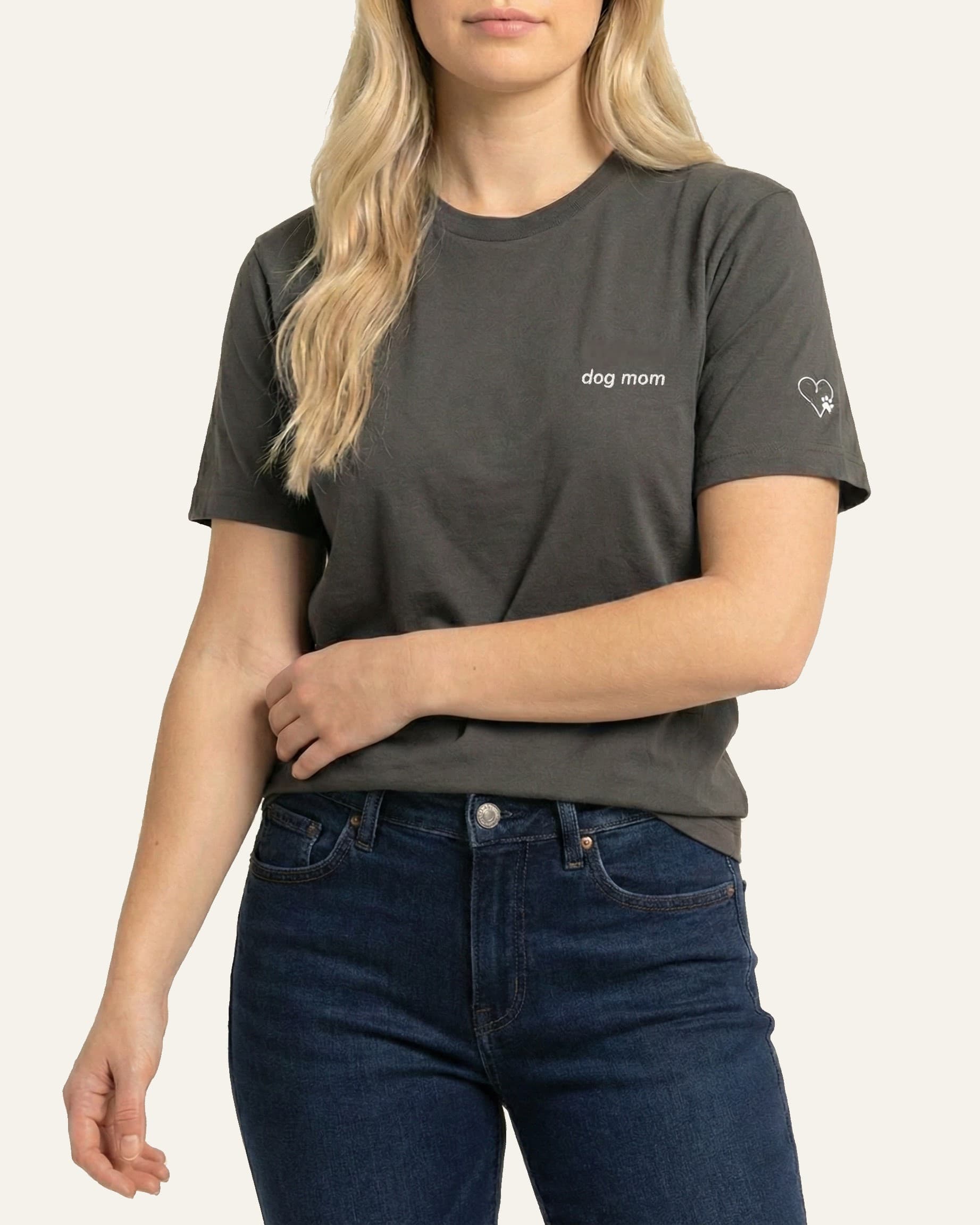 Woman wearing Asphalt t-shirt with minimalist embroidered phrase "dog mom" on left chest. Embroidered Heart and Paw icon on the left sleeve above cuff.