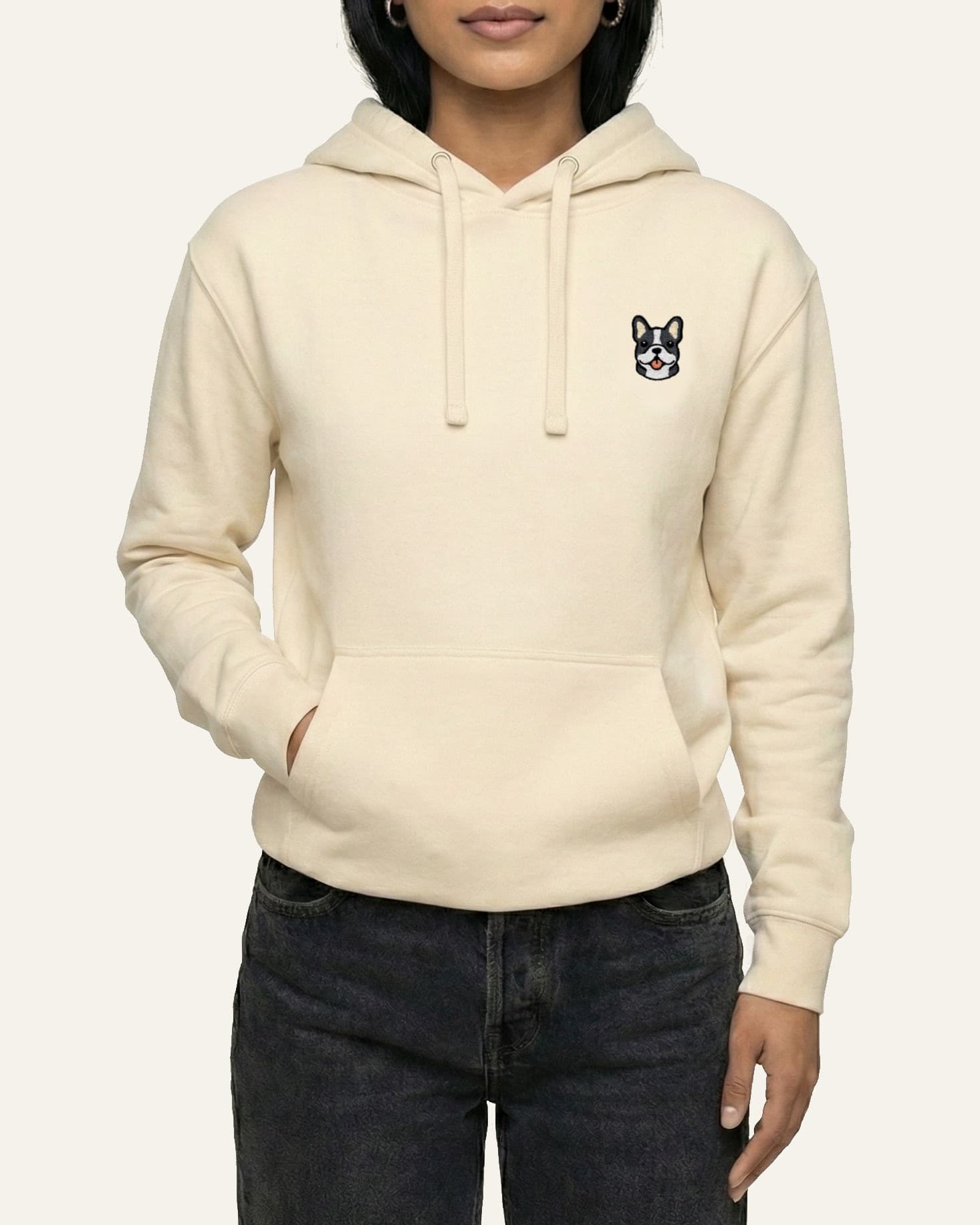 Woman wearing Beige Hoodie with minimalist embroidered #blue-pied Frenchie icon on left chest.