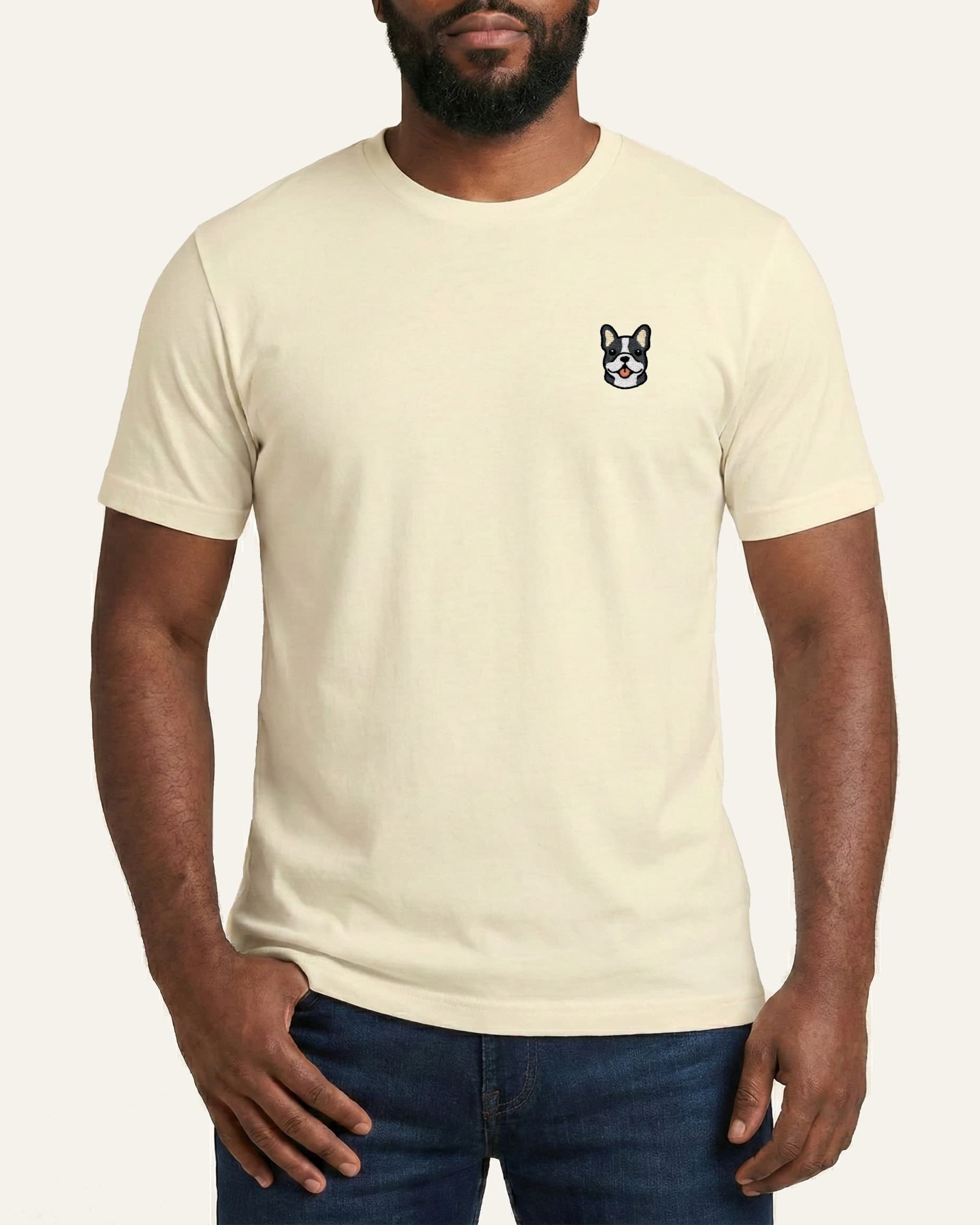 Man wearing Beige T-shirt with minimalist embroidered #blue-pied Frenchie icon on left chest.