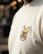 Close up of man wearing Beige T-shirt with minimalist embroidered #fawn Frenchie icon on left chest.