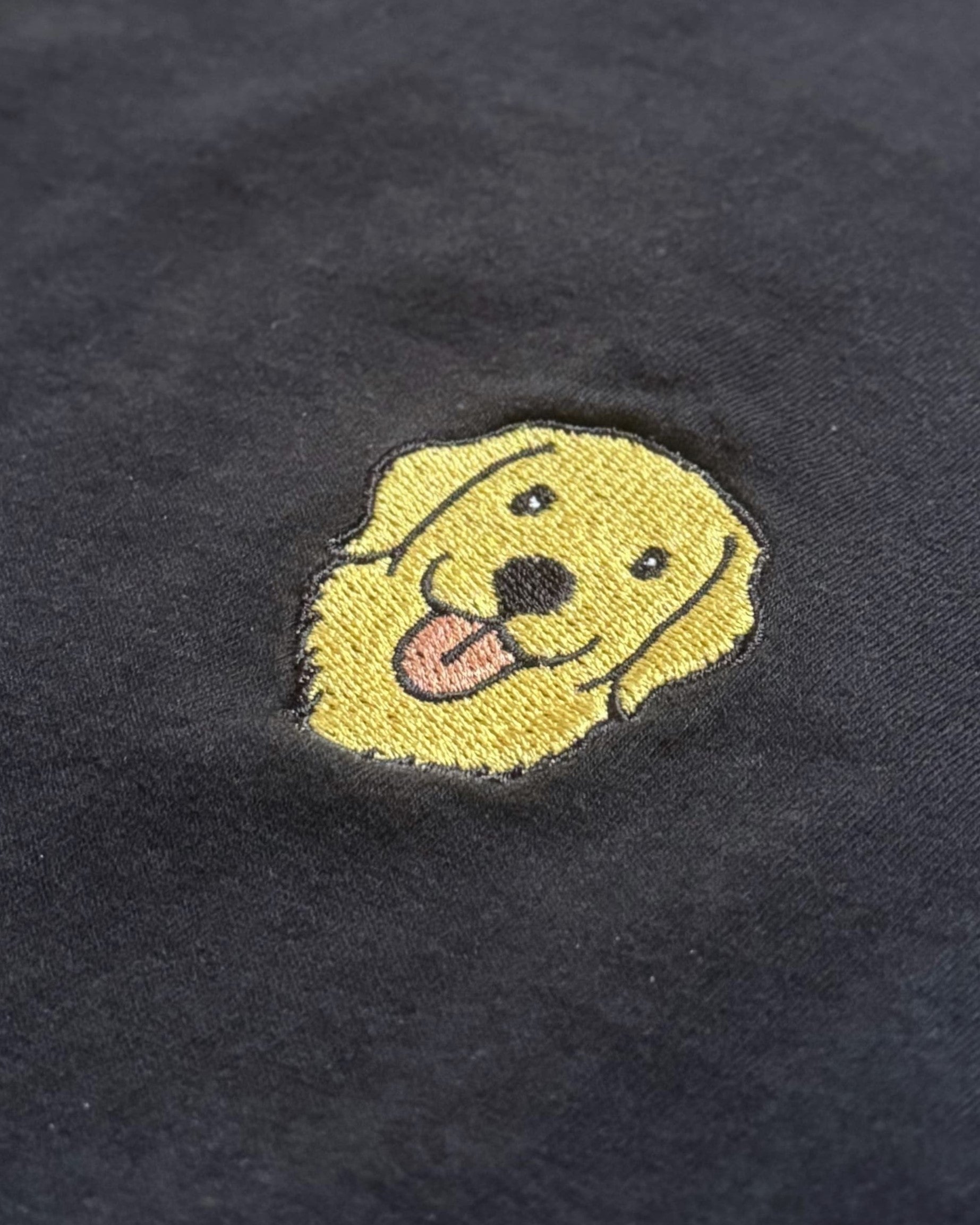Close-up detail of Golden Retriever embroidery on Black fabric showing stitch texture.