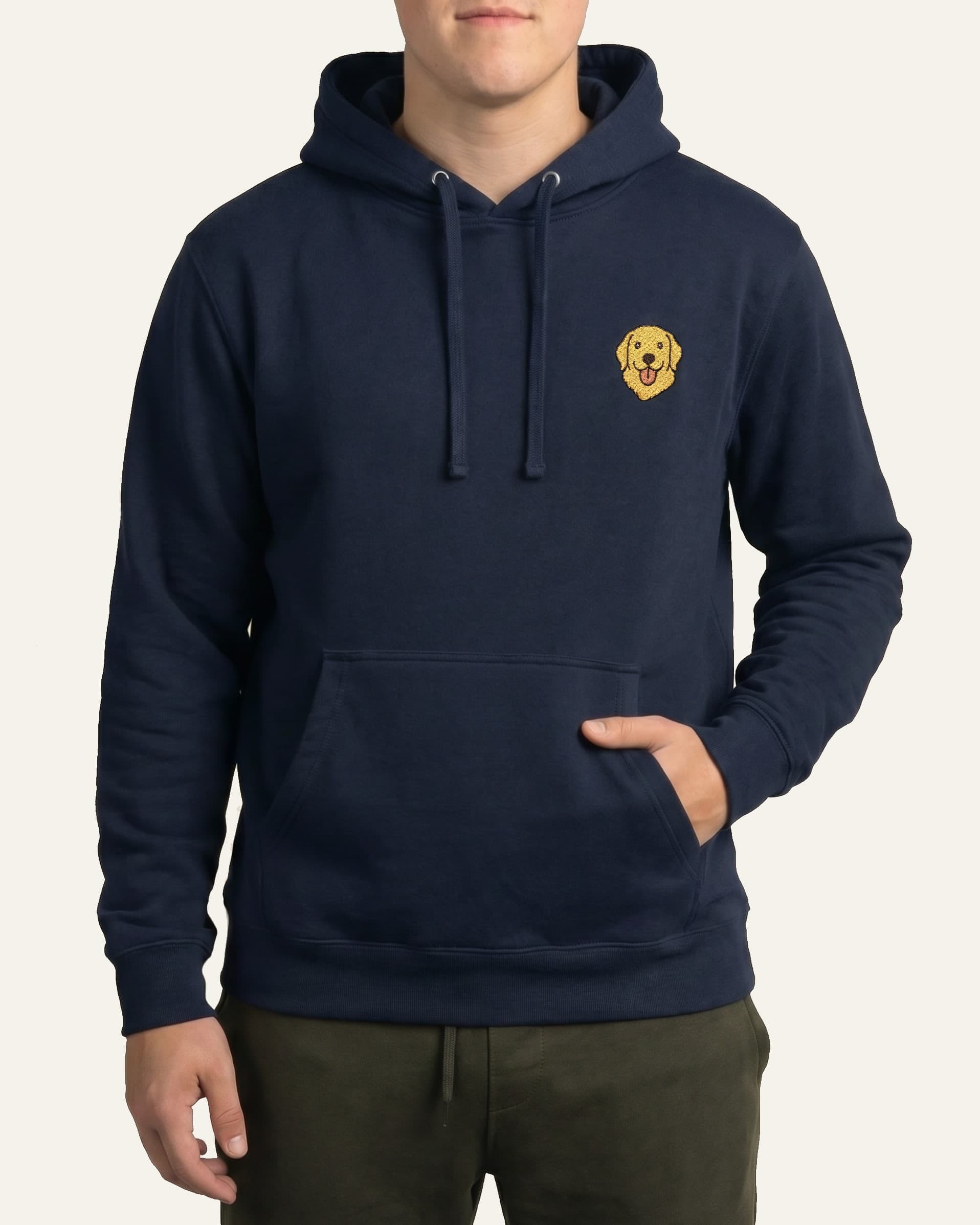 Man wearing Navy Hoodie with minimalist embroidered Golden Retriever icon on left chest.