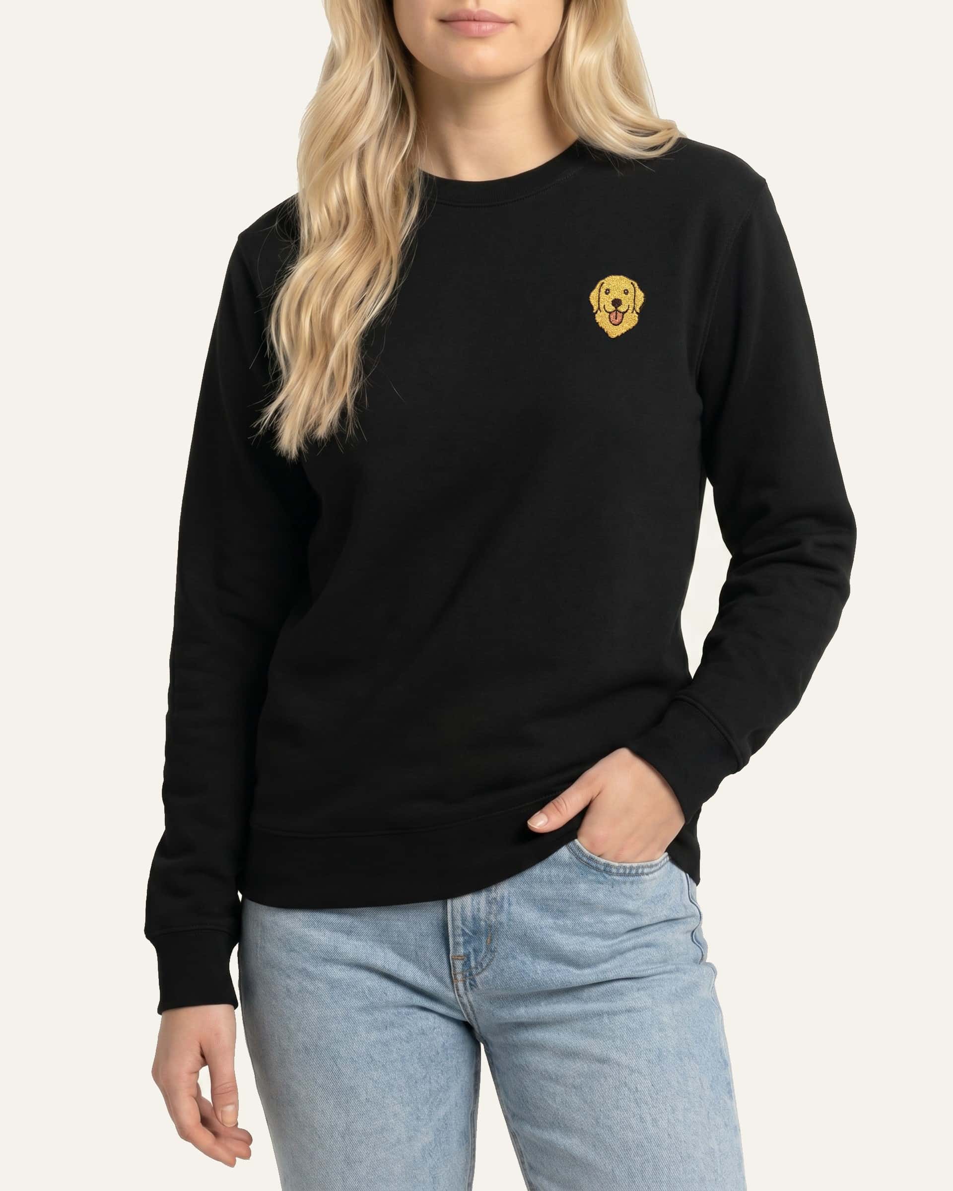 Woman wearing Black Sweatshirt with minimalist embroidered Golden Retriever icon on left chest.