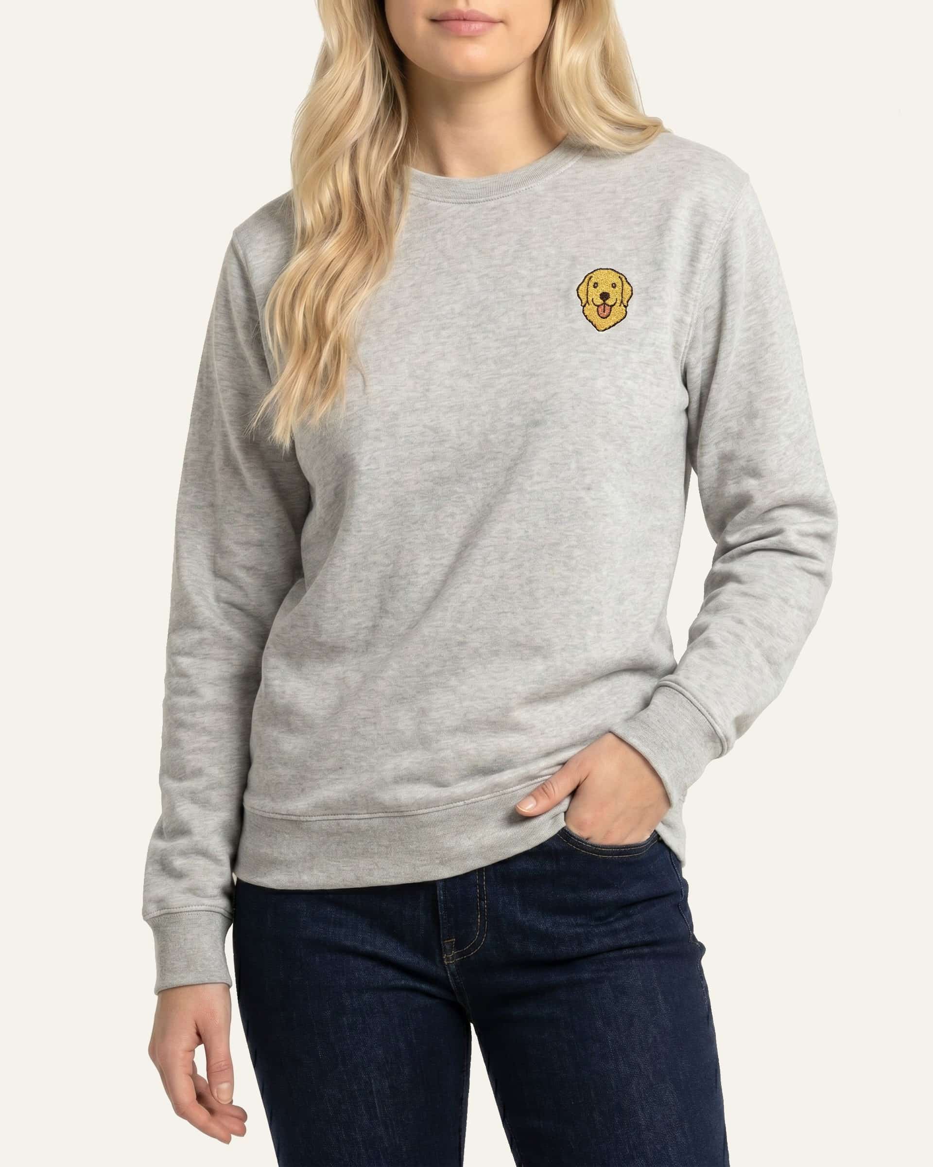 Woman wearing Light Grey Heather Sweatshirt with minimalist embroidered Golden Retriever icon on left chest.