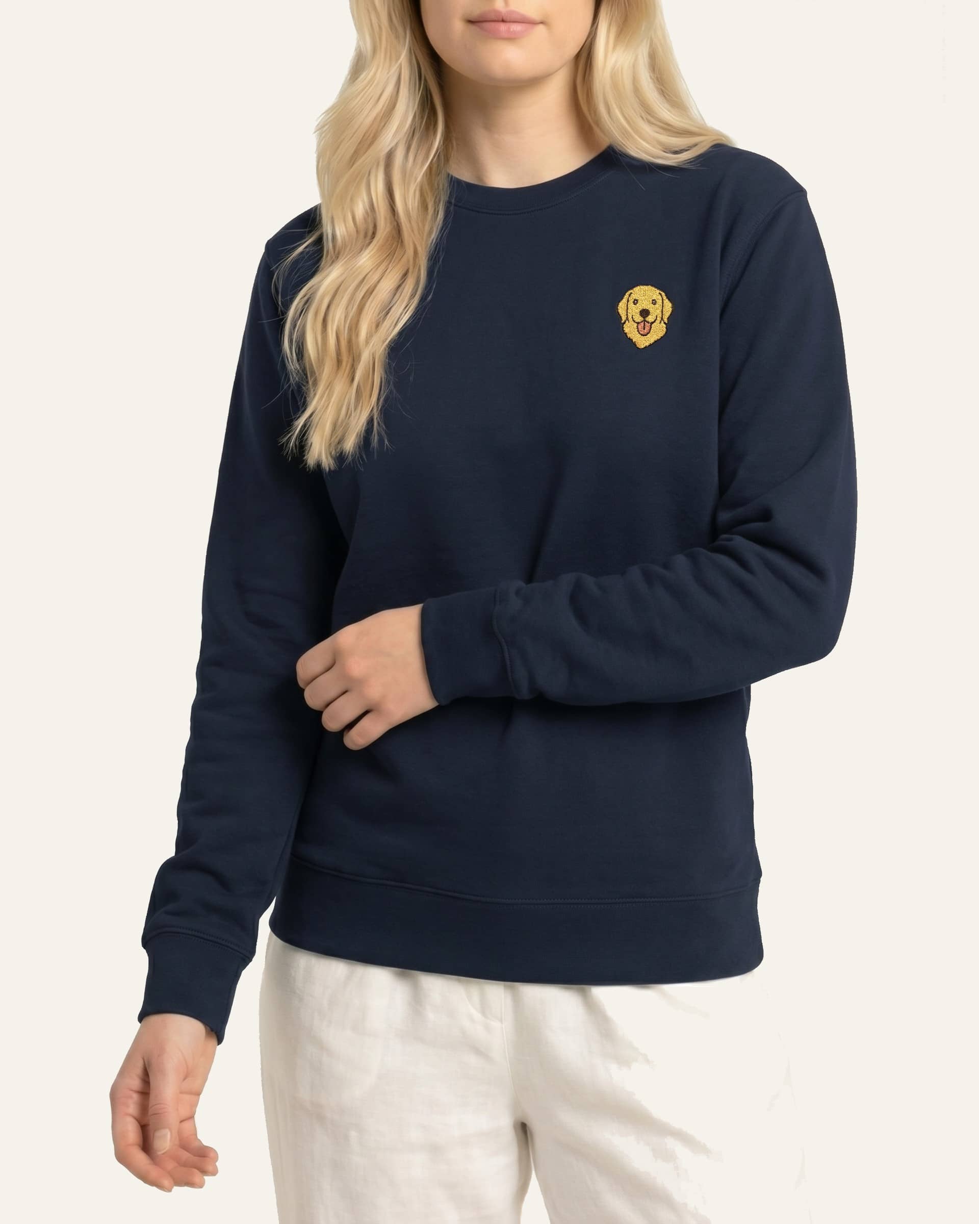 Woman wearing Navy Sweatshirt with minimalist embroidered Golden Retriever icon on left chest.