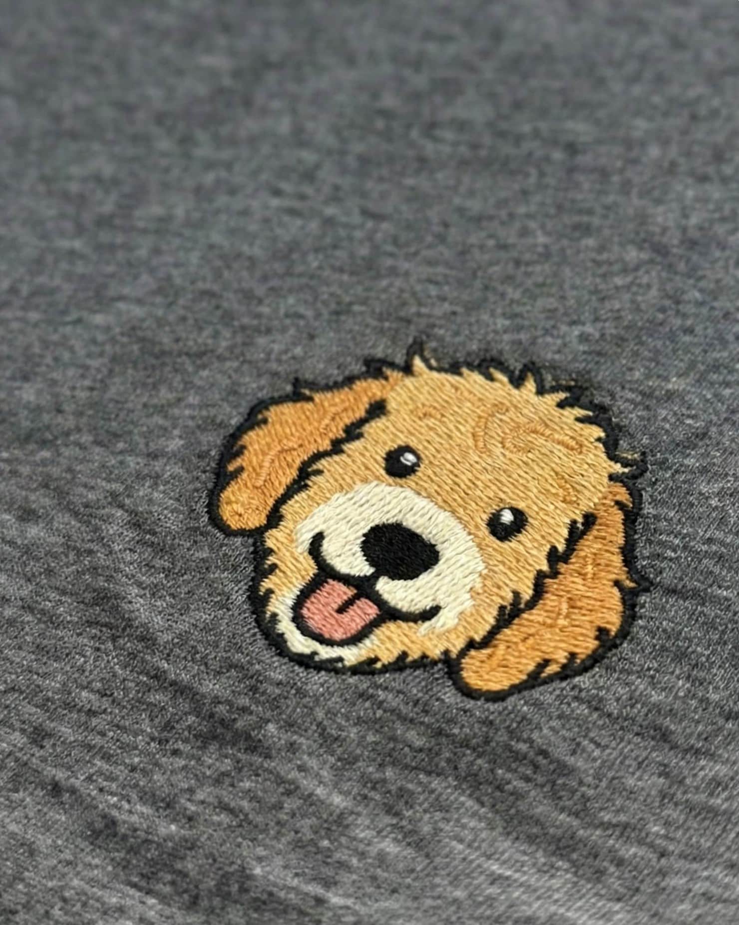 Close up of minimalist embroidered Goldendoodle icon on left chest.
