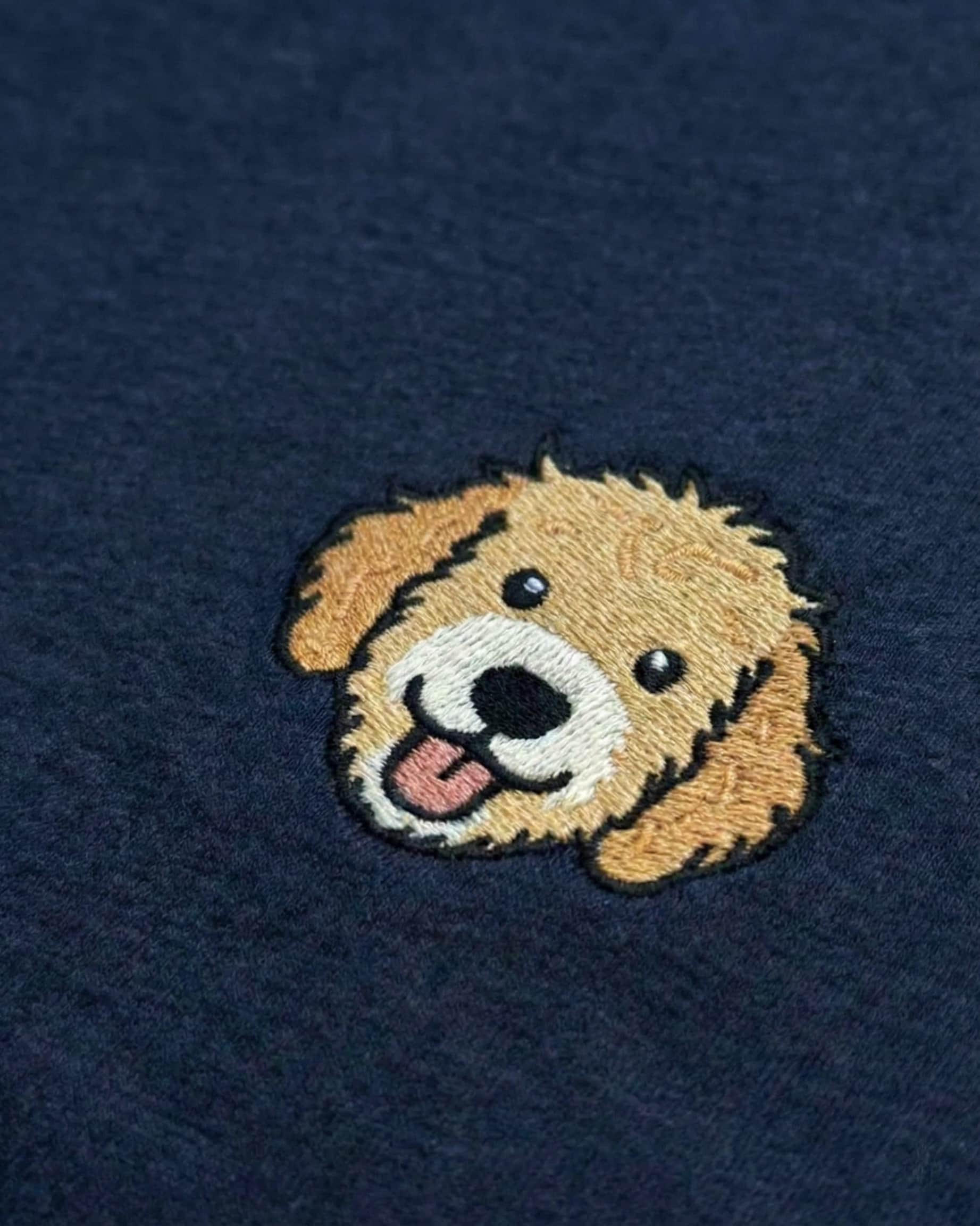Close up of Navy Sweatshirt with minimalist embroidered Goldendoodle icon on left chest.