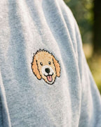 Close-up detail of Goldendoodle embroidery on light grey heather fabric showing stitch texture.