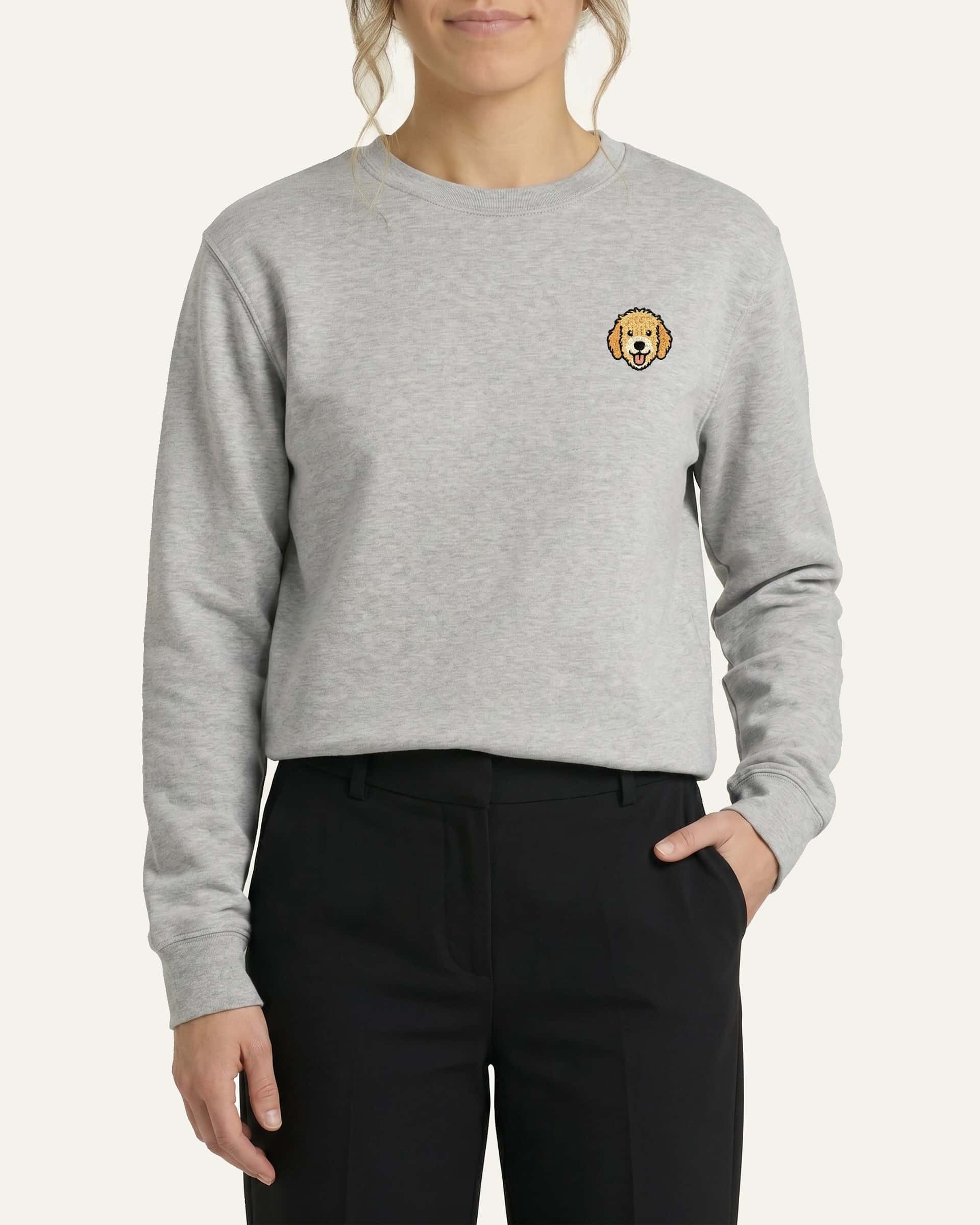 Woman wearing Light Grey Sweatshirt with minimalist embroidered Goldendoodle icon on left chest.