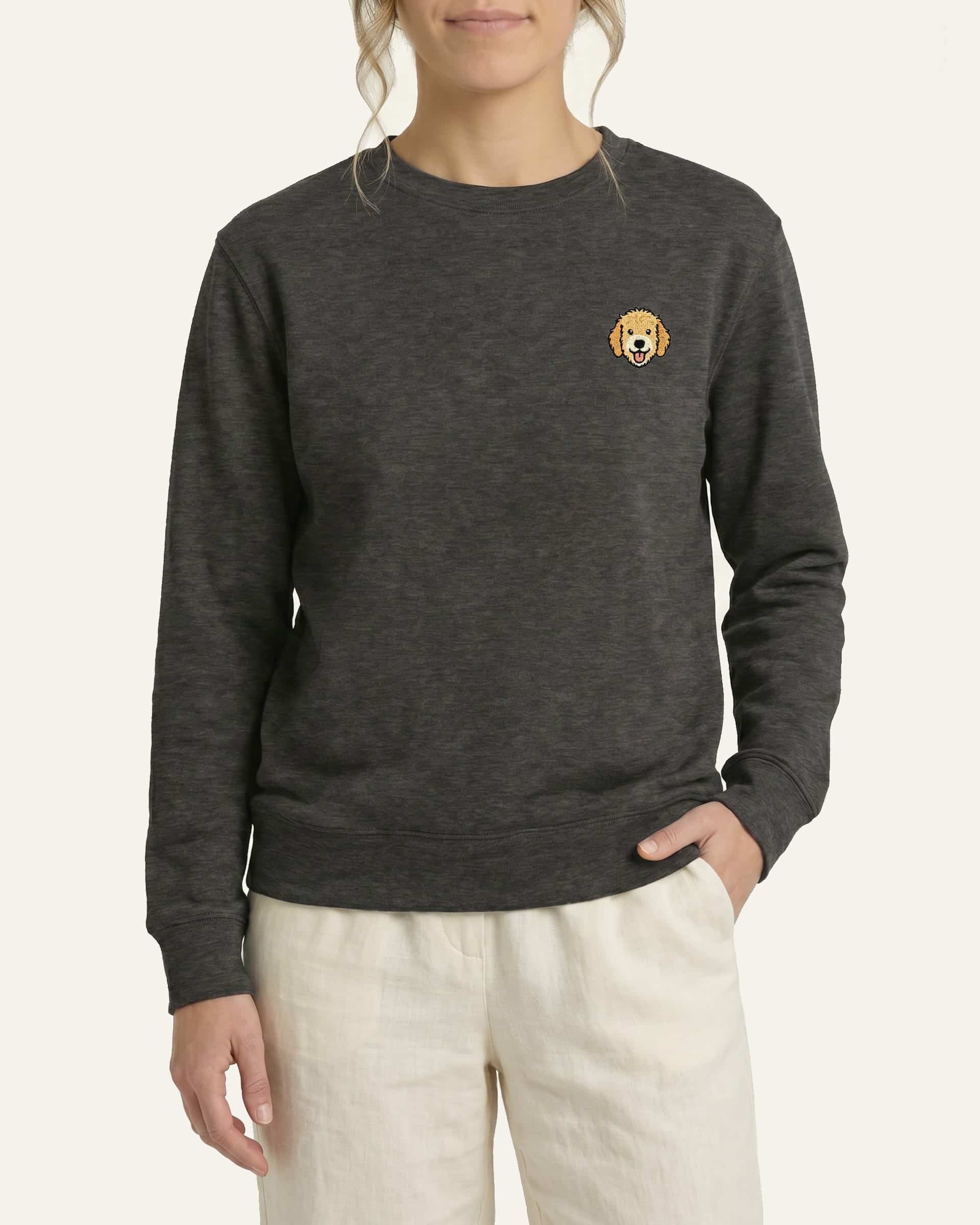 Woman wearing Dark Grey Sweatshirt with minimalist embroidered Goldendoodle icon on left chest.
