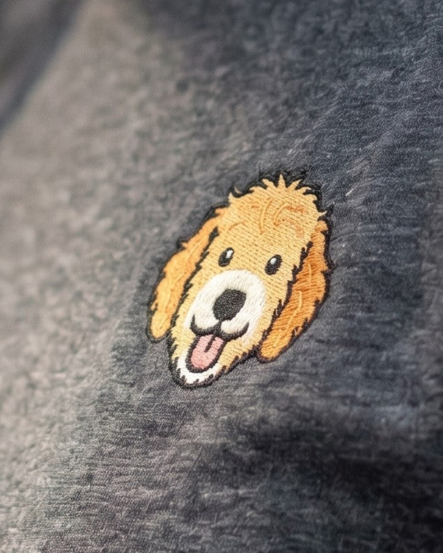 Close-up detail of Goldendoodle embroidery on dark grey heather fabric showing stitch texture.