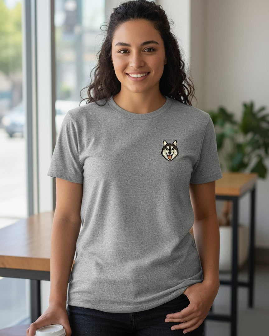 Woman wearing Light Grey Heather T-shirt with minimalist embroidered Husky icon on left chest.