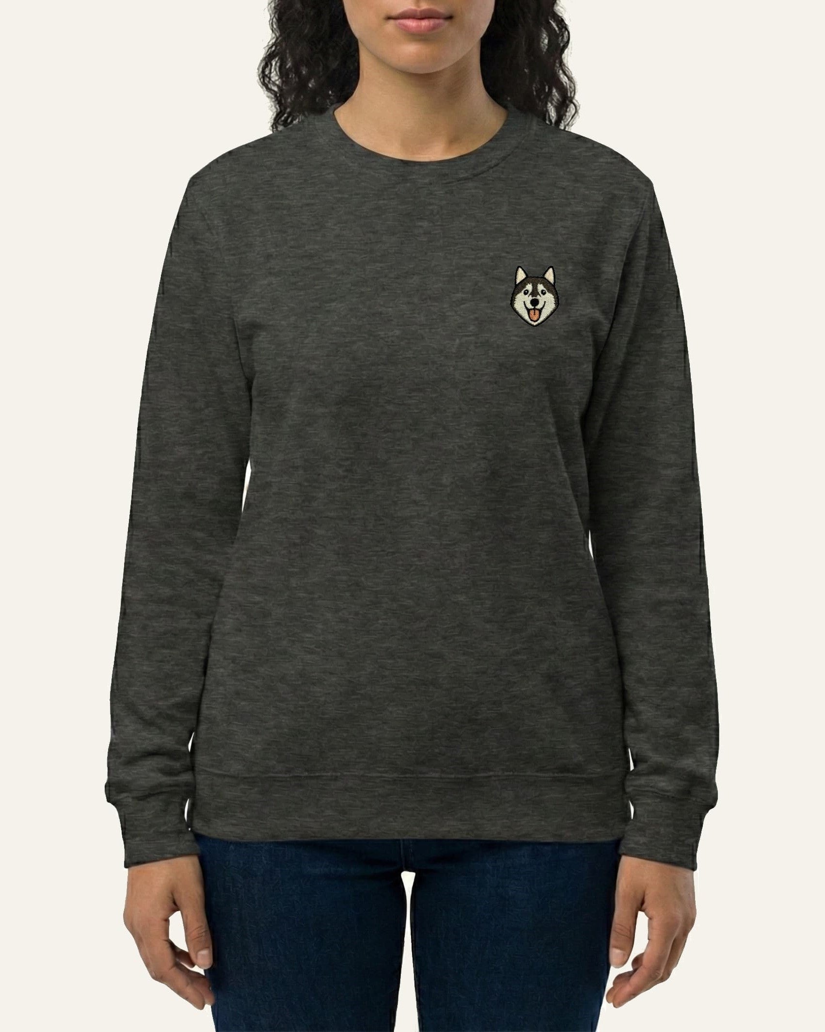 Woman wearing Dark Grey Heather Sweatshirt with minimalist embroidered Husky icon on left chest.