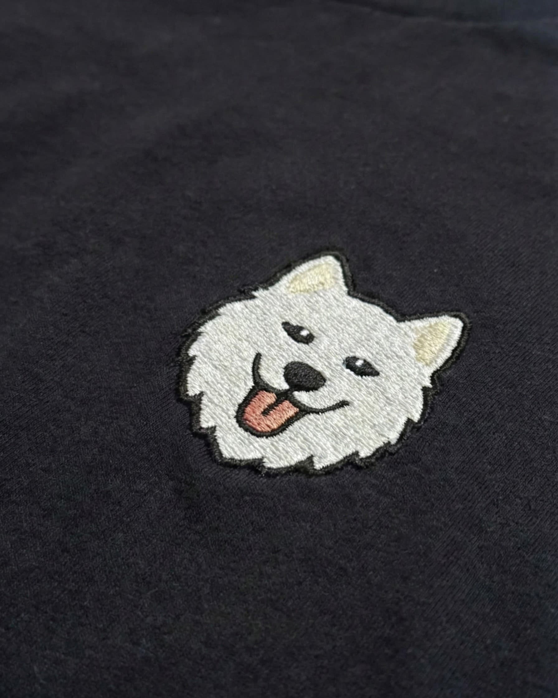 Close-up detail of Samoyed embroidery on Black fabric showing stitch texture.