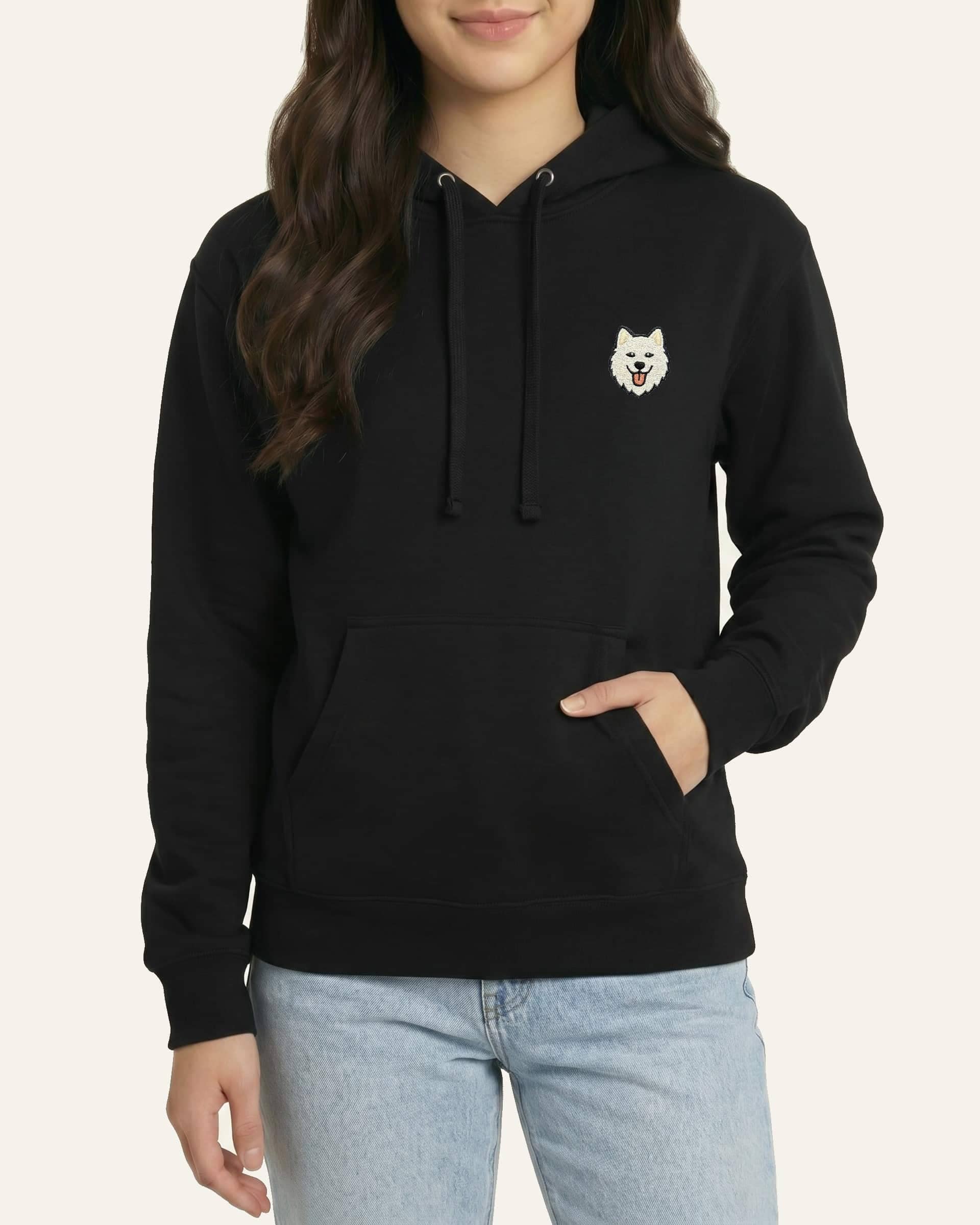 Woman wearing Black Hoodie with minimalist embroidered Samoyed icon on left chest.