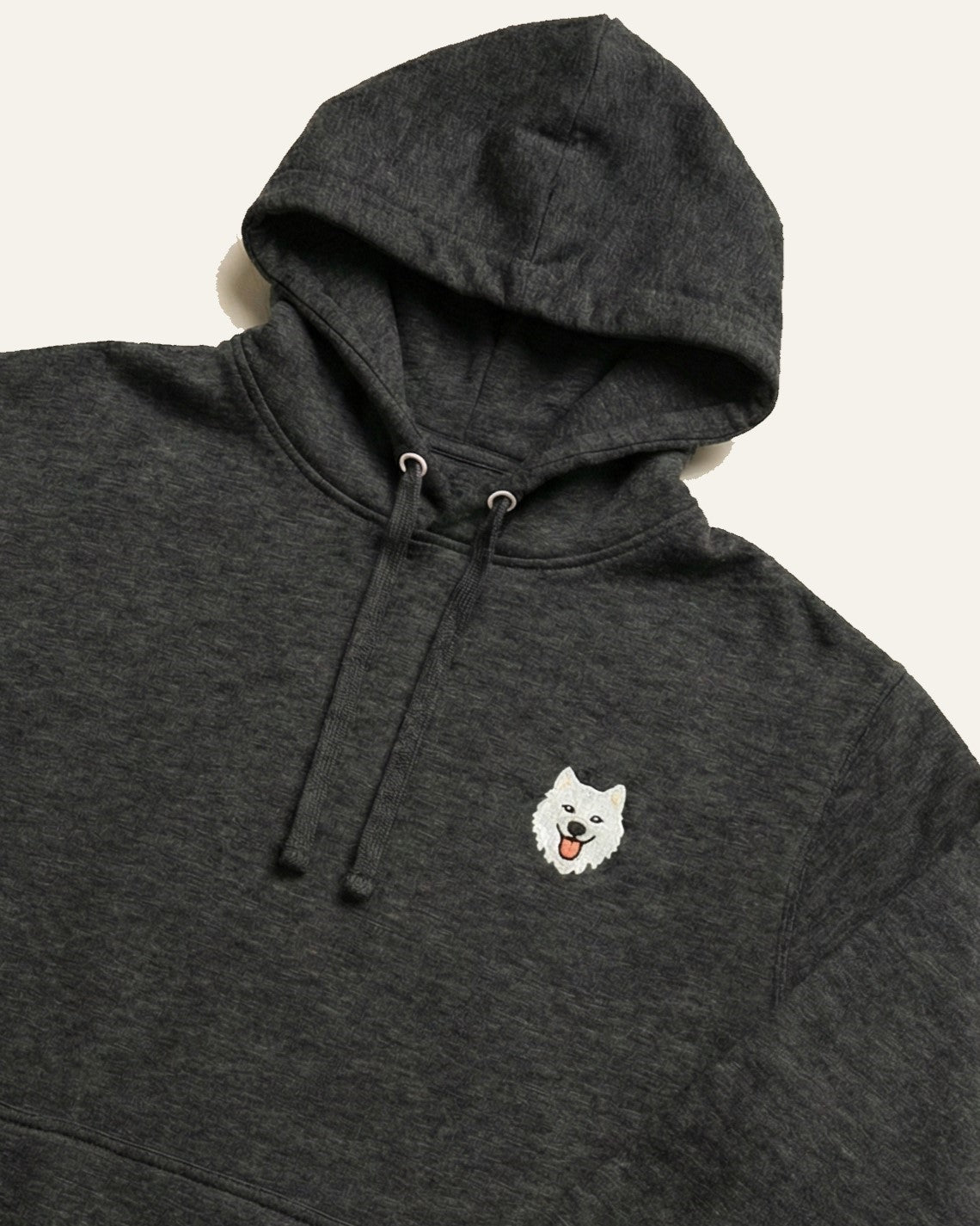 Close up of Dark Grey Heather Hoodie with minimalist embroidered Samoyed icon on left chest.