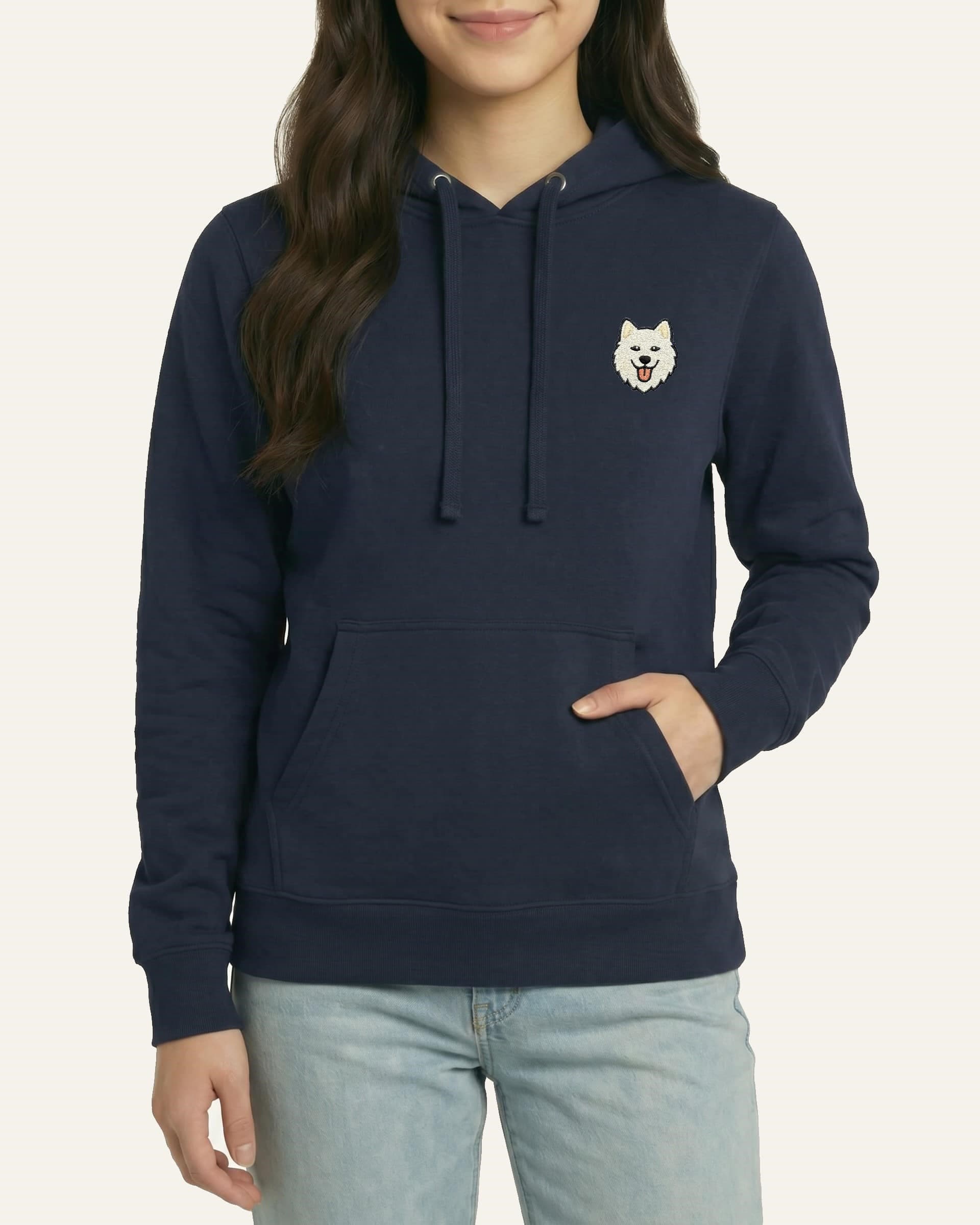 Woman wearing Navy Hoodie with minimalist embroidered Samoyed icon on left chest.