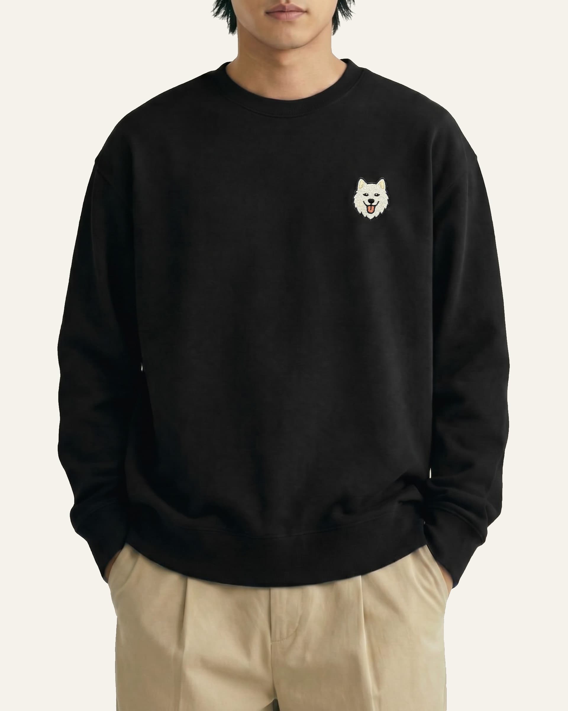 Man wearing Black Sweatshirt with minimalist embroidered Samoyed icon on left chest.