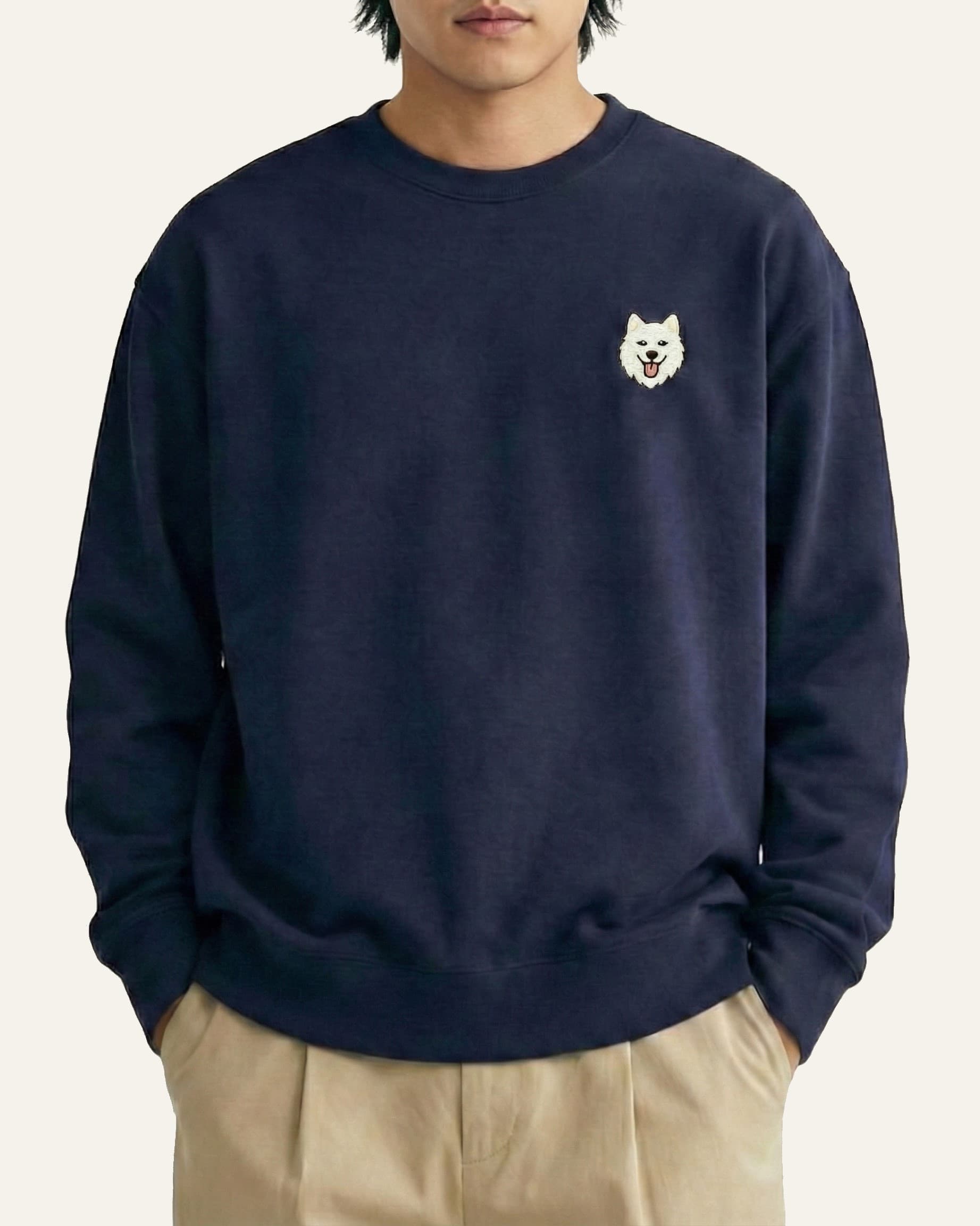 Man wearing Navy Sweatshirt with minimalist embroidered Samoyed icon on left chest.