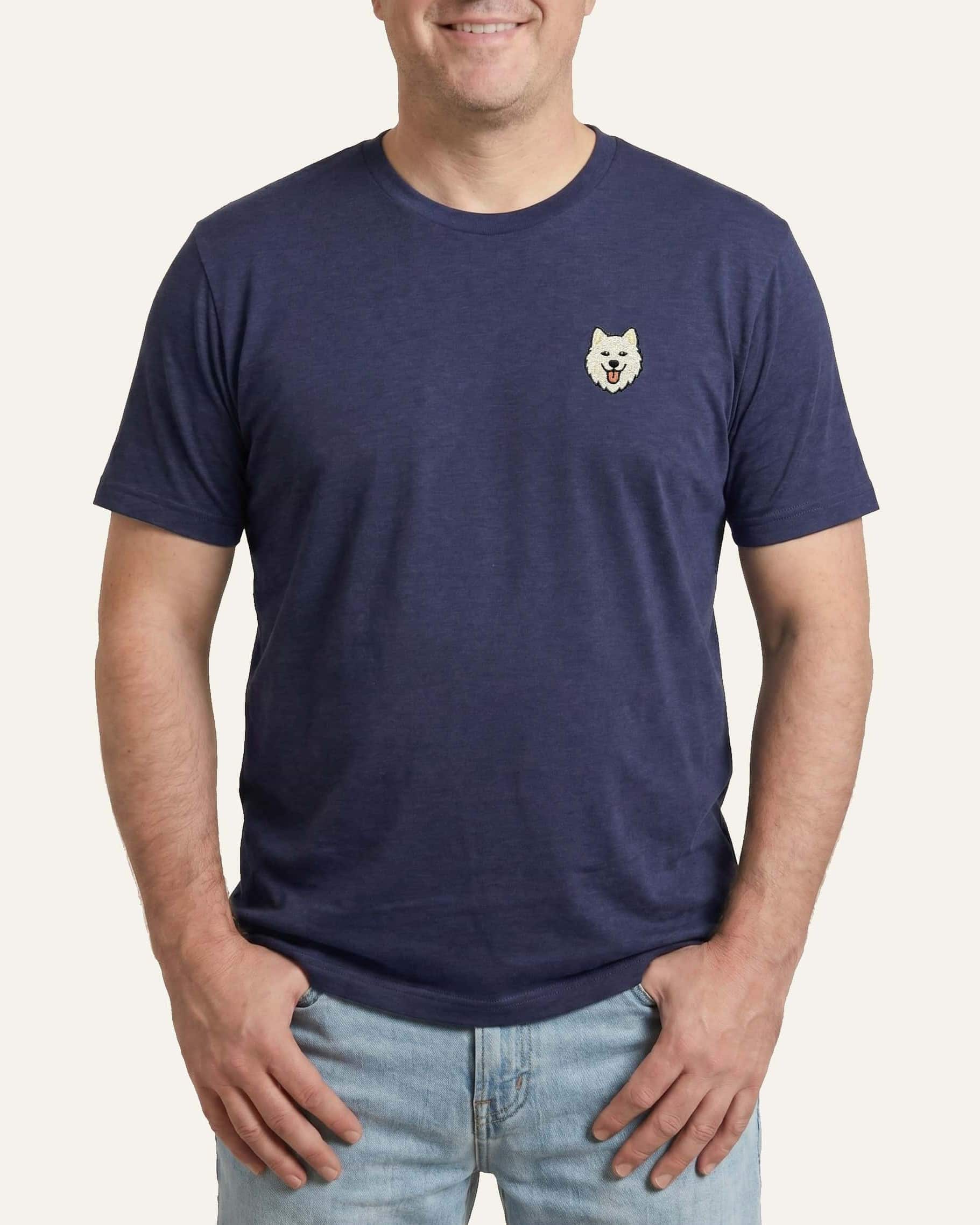Man wearing Navy Heather T-shirt with minimalist embroidered Samoyed icon on left chest.