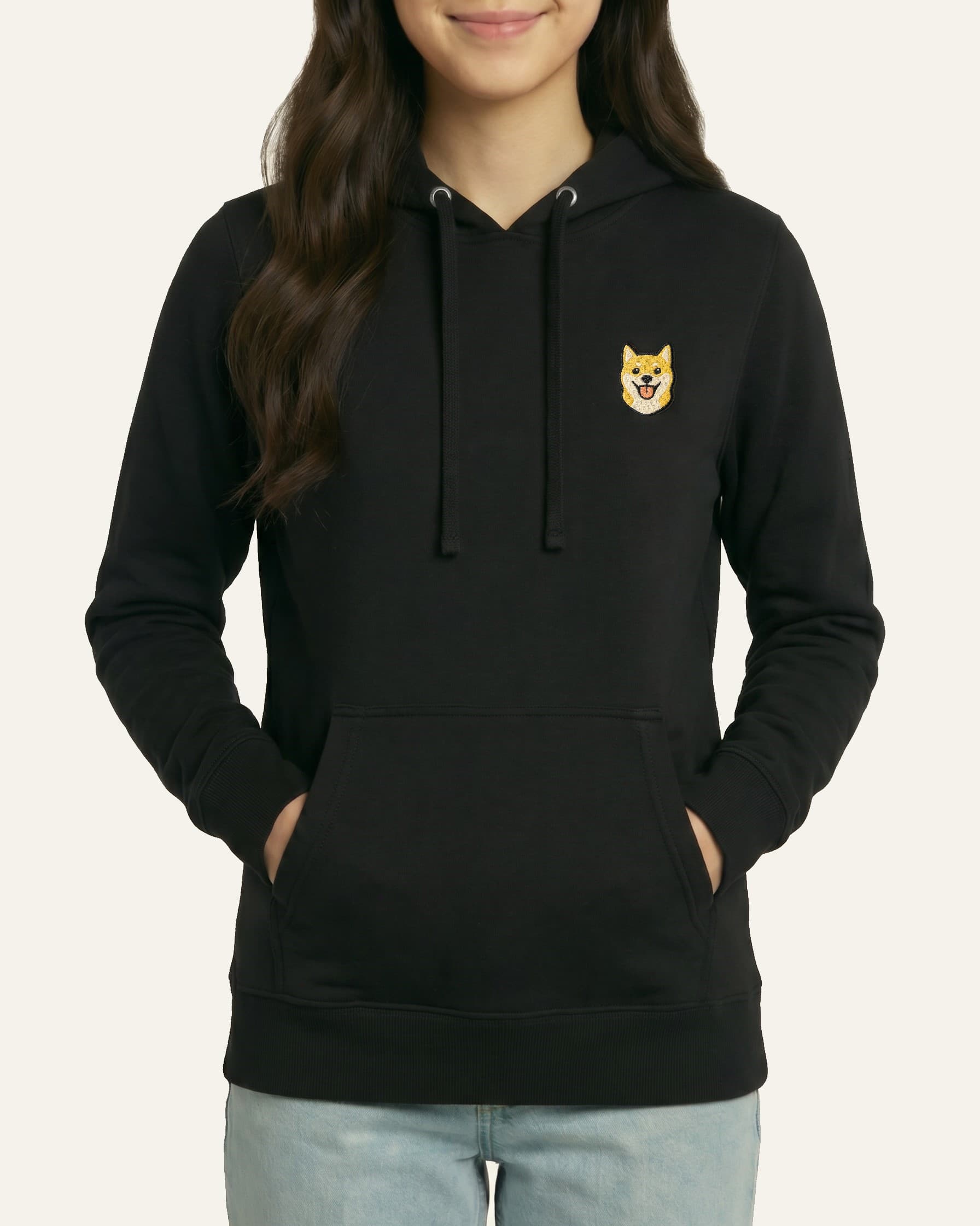 Woman wearing Black Hoodie with minimalist embroidered Shiba Inu icon on left chest.