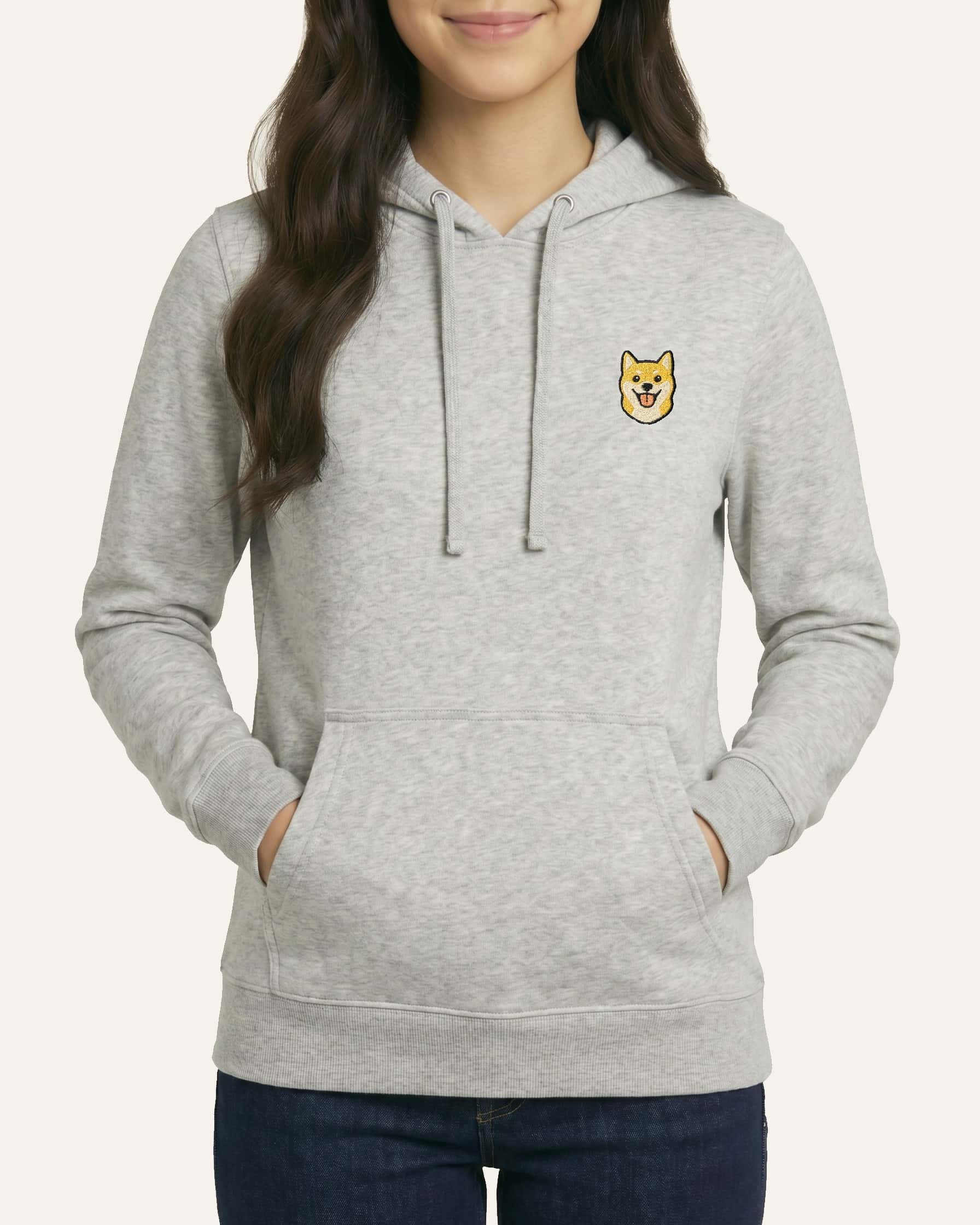 Woman wearing Light Grey Heather Hoodie with minimalist embroidered Shiba Inu icon on left chest.