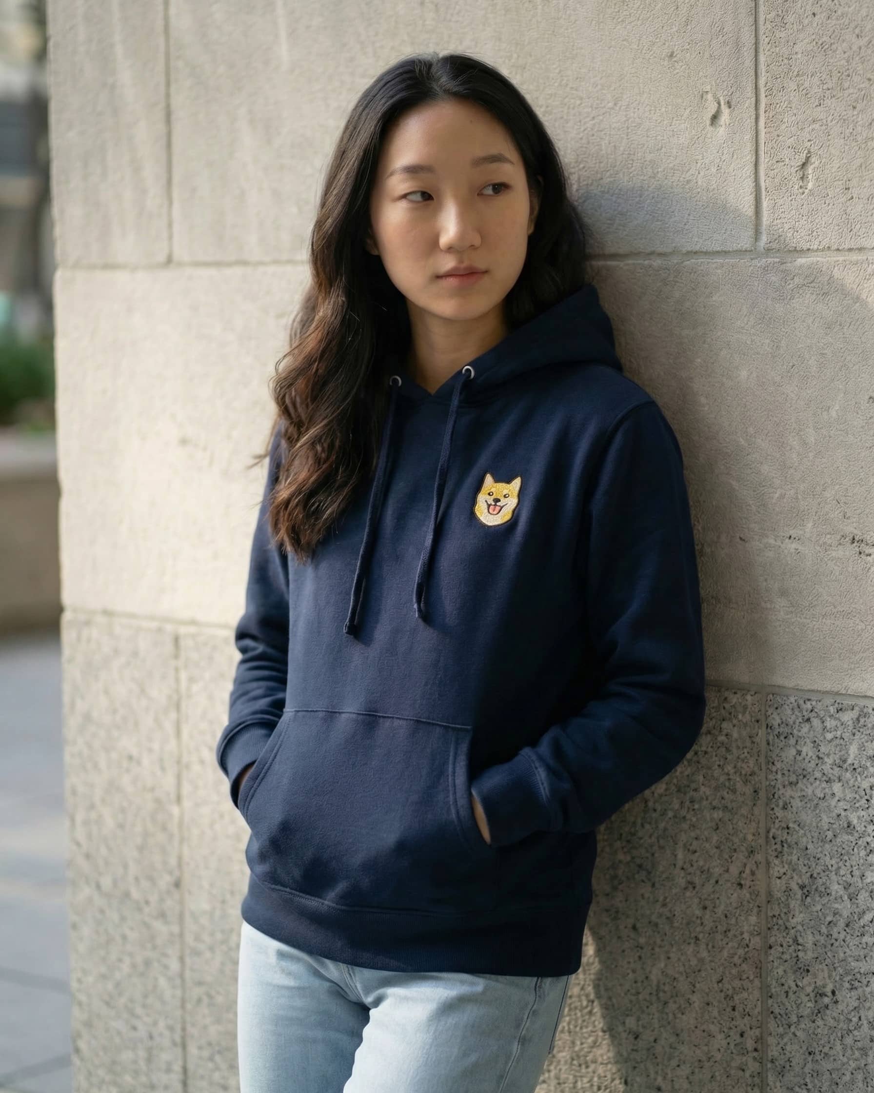 Woman wearing Navy Hoodie with minimalist embroidered Shiba Inu icon on left chest.
