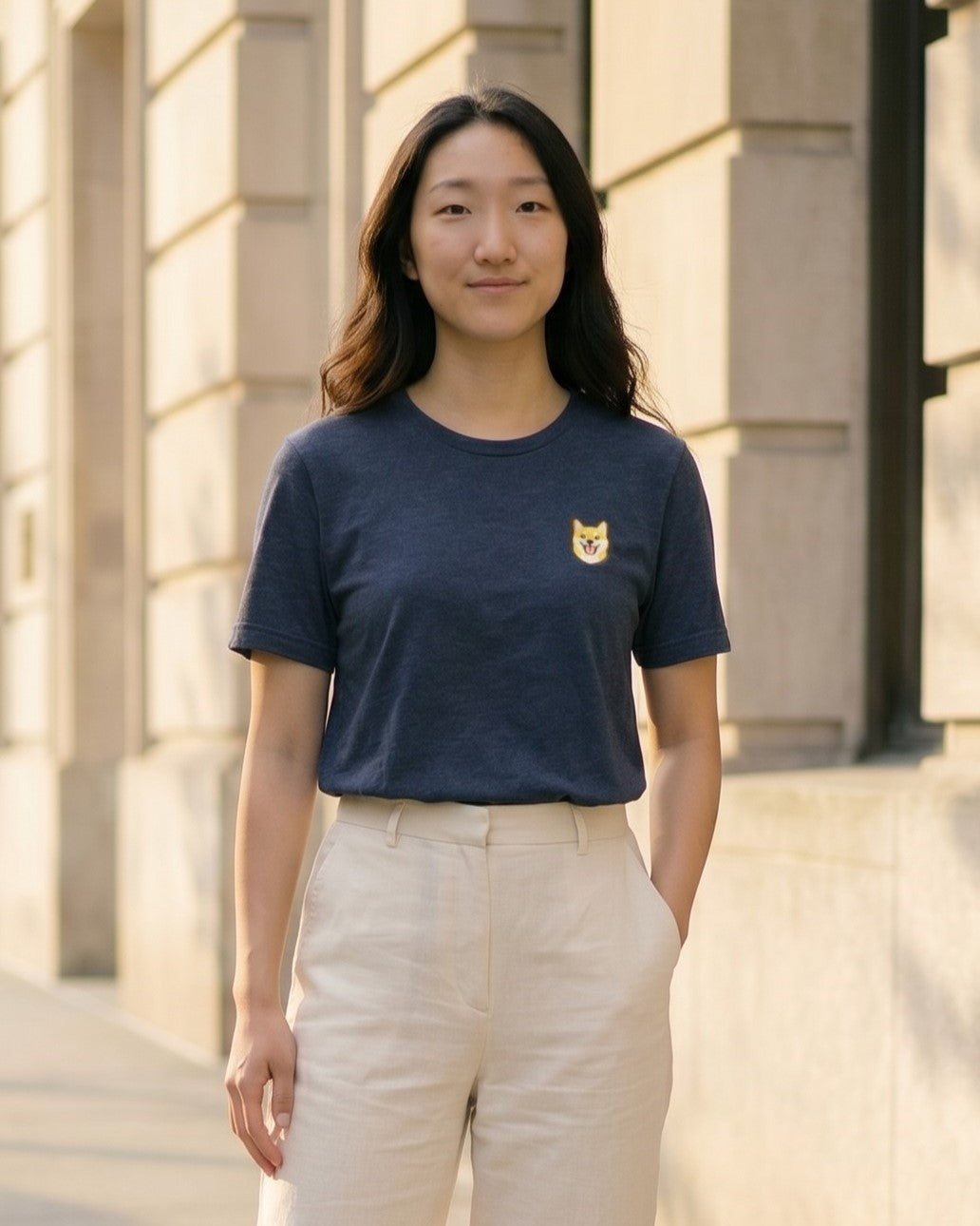 Woman wearing Navy Heather T-shirt with minimalist embroidered Shiba Inu icon on left chest.
