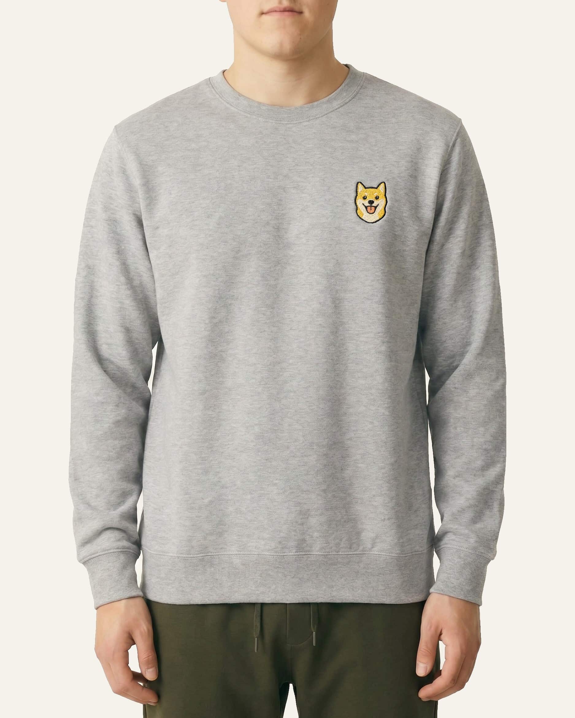 Man wearing Light Grey Heather Sweatshirt with minimalist embroidered Shiba Inu icon on left chest.