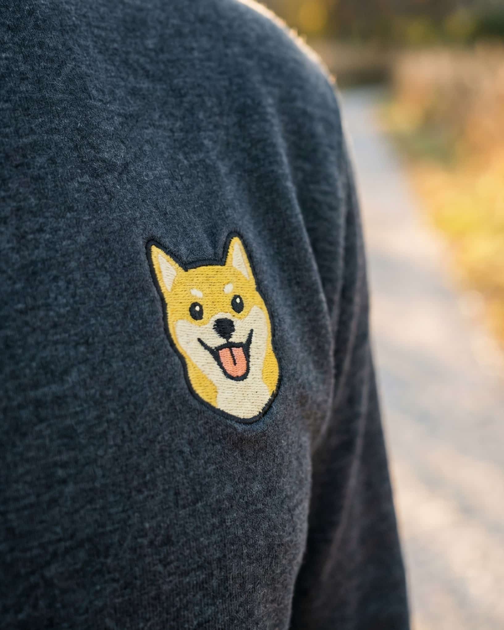Close-up detail of Shiba Inu embroidery on dark grey heather fabric showing stitch texture.