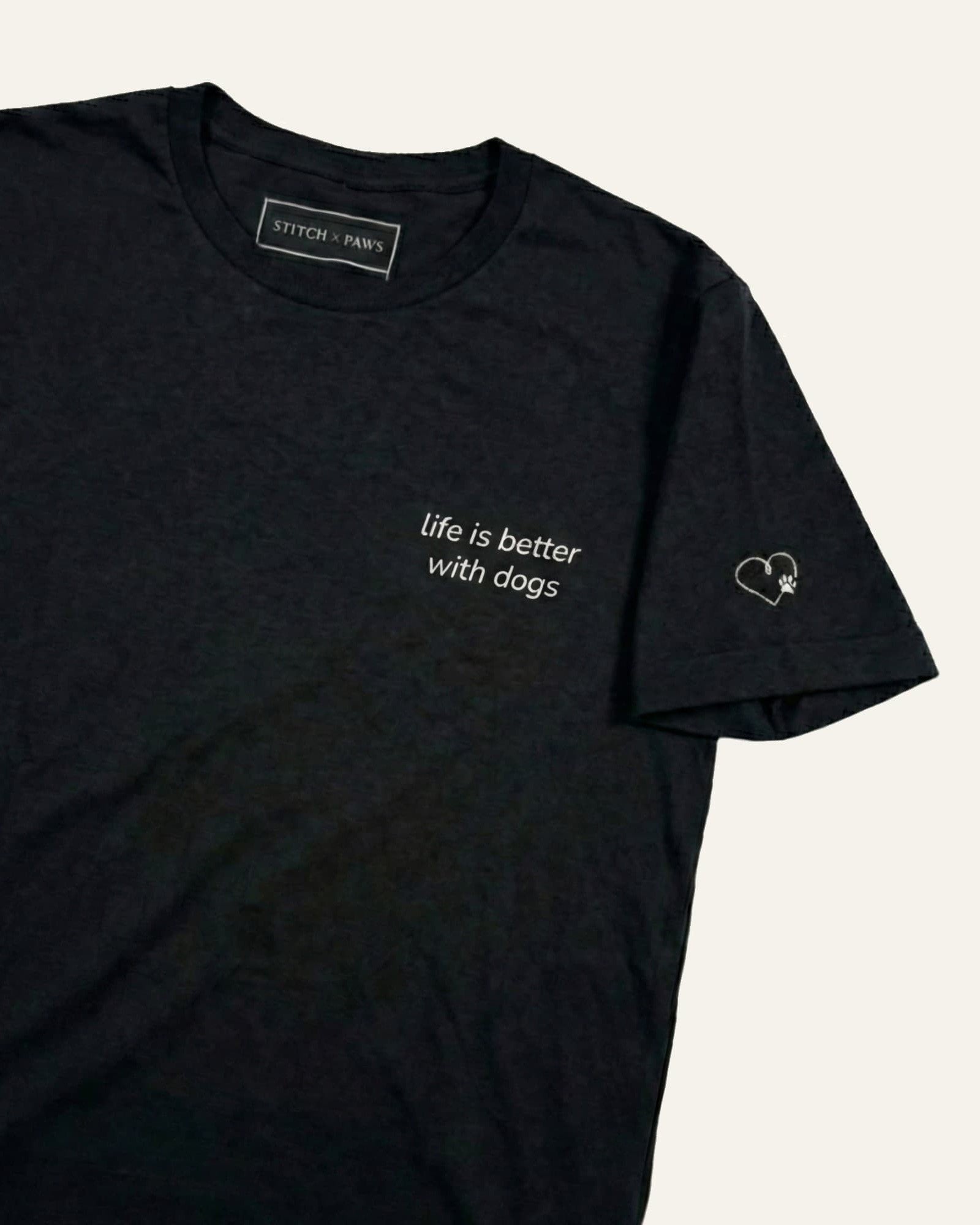 Black t-shirt with minimalist embroidered phrase "life is better with dogs" on left chest. Embroidered Heart and Paw icon on the left sleeve above cuff.