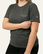 Woman wearing Asphalt t-shirt with minimalist embroidered phrase "my best friend has paws" on left chest. Embroidered Heart and Paw icon on the left sleeve above cuff.