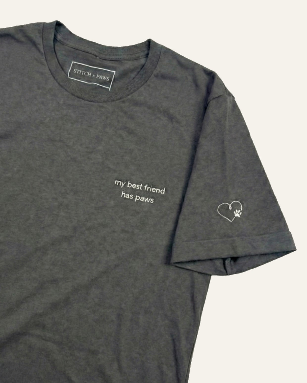 Asphalt t-shirt with minimalist embroidered phrase "my best friend has paws" on left chest. Embroidered Heart and Paw icon on the left sleeve above cuff.
